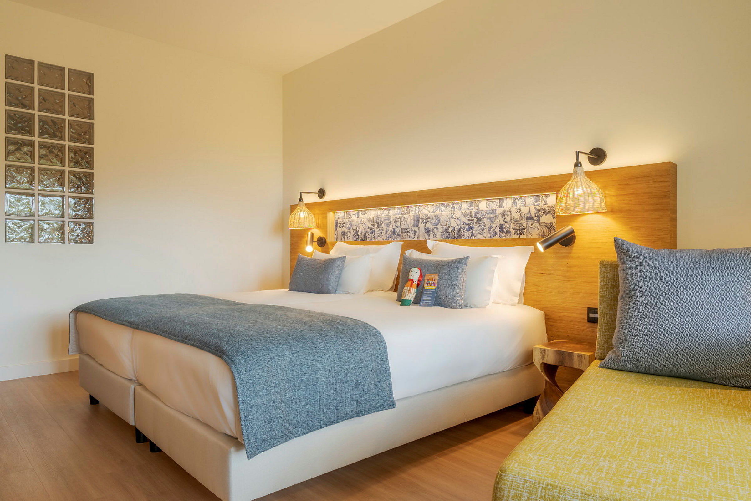 Moderne hotellrom med dobbeltseng, hvitt sengetøy og blått sengeteppe. (AI-generert tekst)