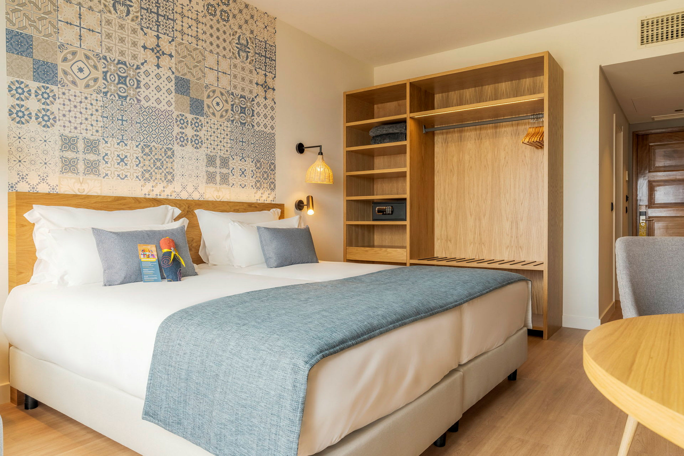 Et hotellrom med en dobbeltseng, et garderobeskap med hyller og en dekorert vegg. (AI-generert tekst)