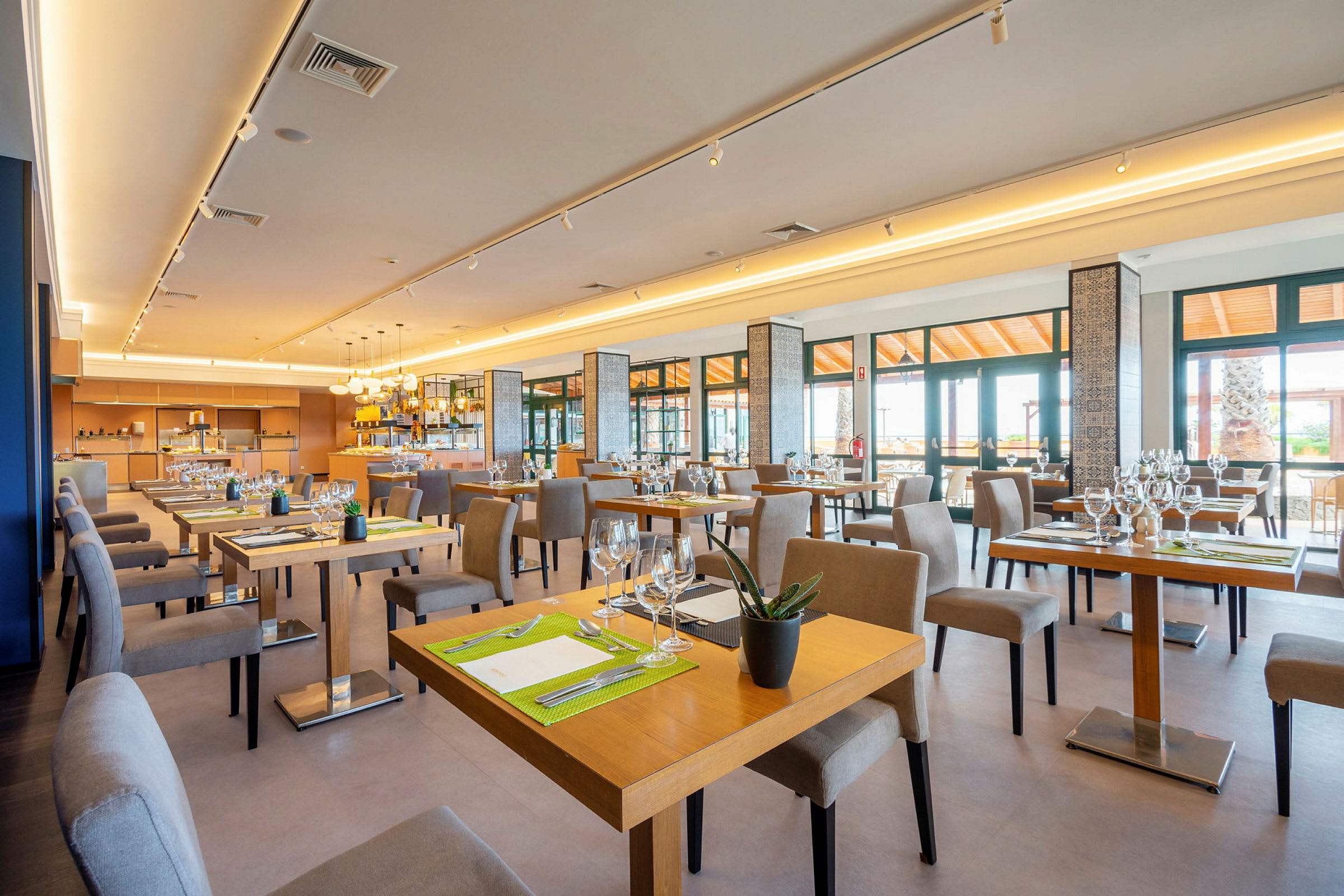 Bilde av en lys og moderne restaurant med bord og stoler. (AI-generert tekst)