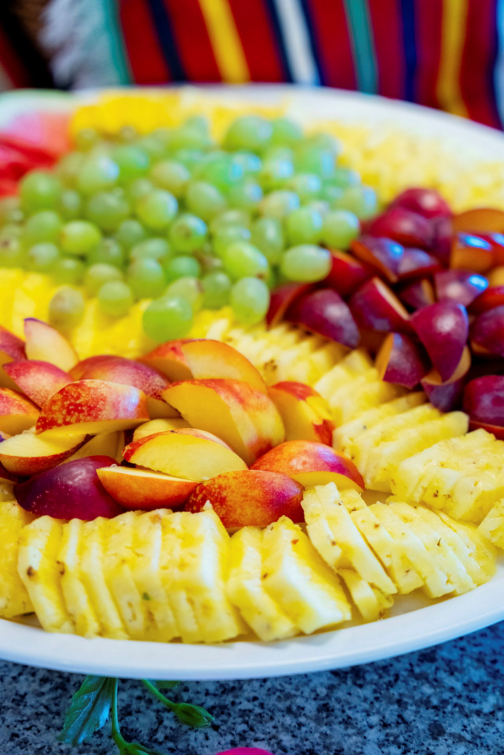 En tallerken med skivet ananas, druer, nektariner og røde frukter. (AI-generert tekst)