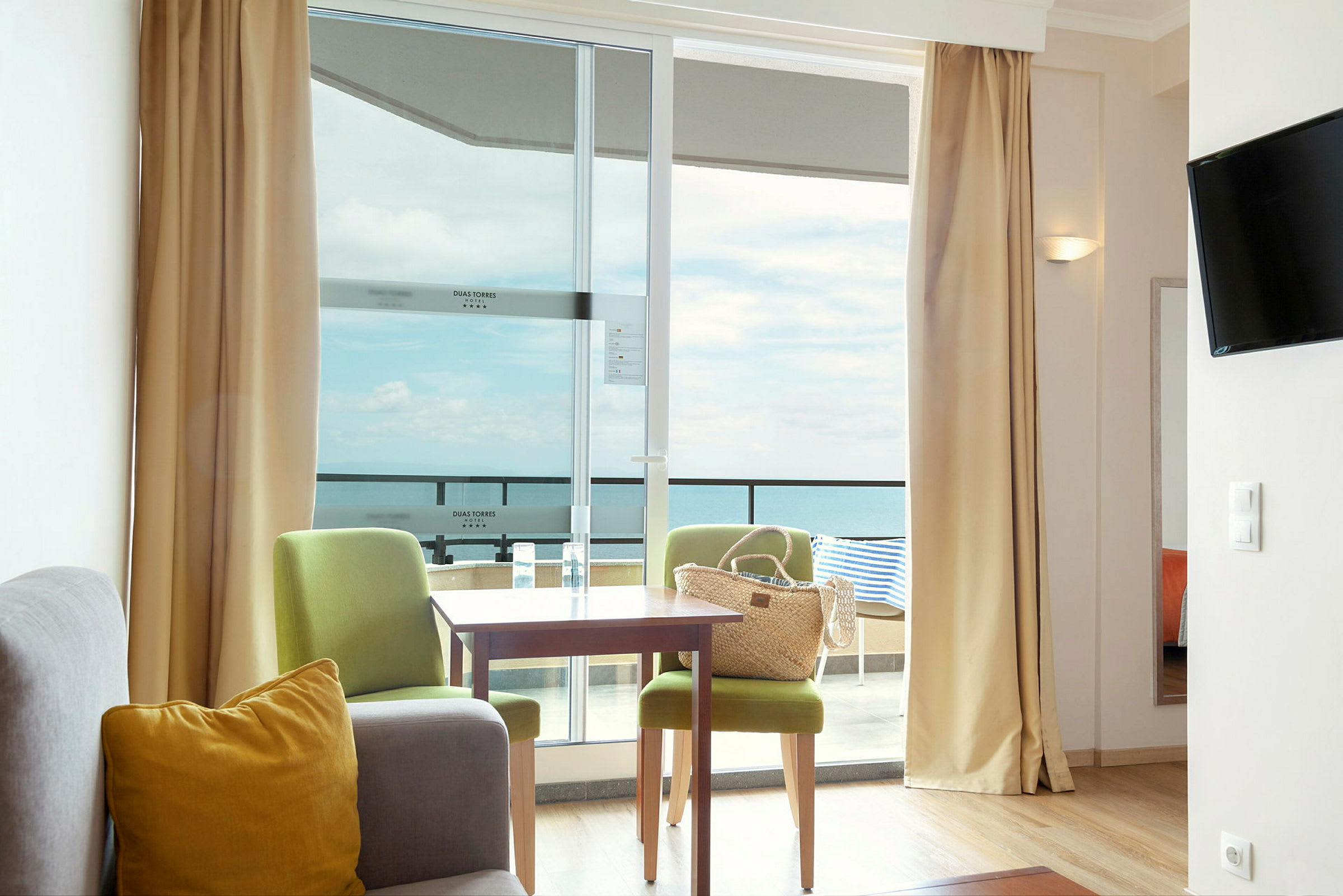 Et hotellrom med sittegruppe og utsikt mot havet. (AI-generert tekst)