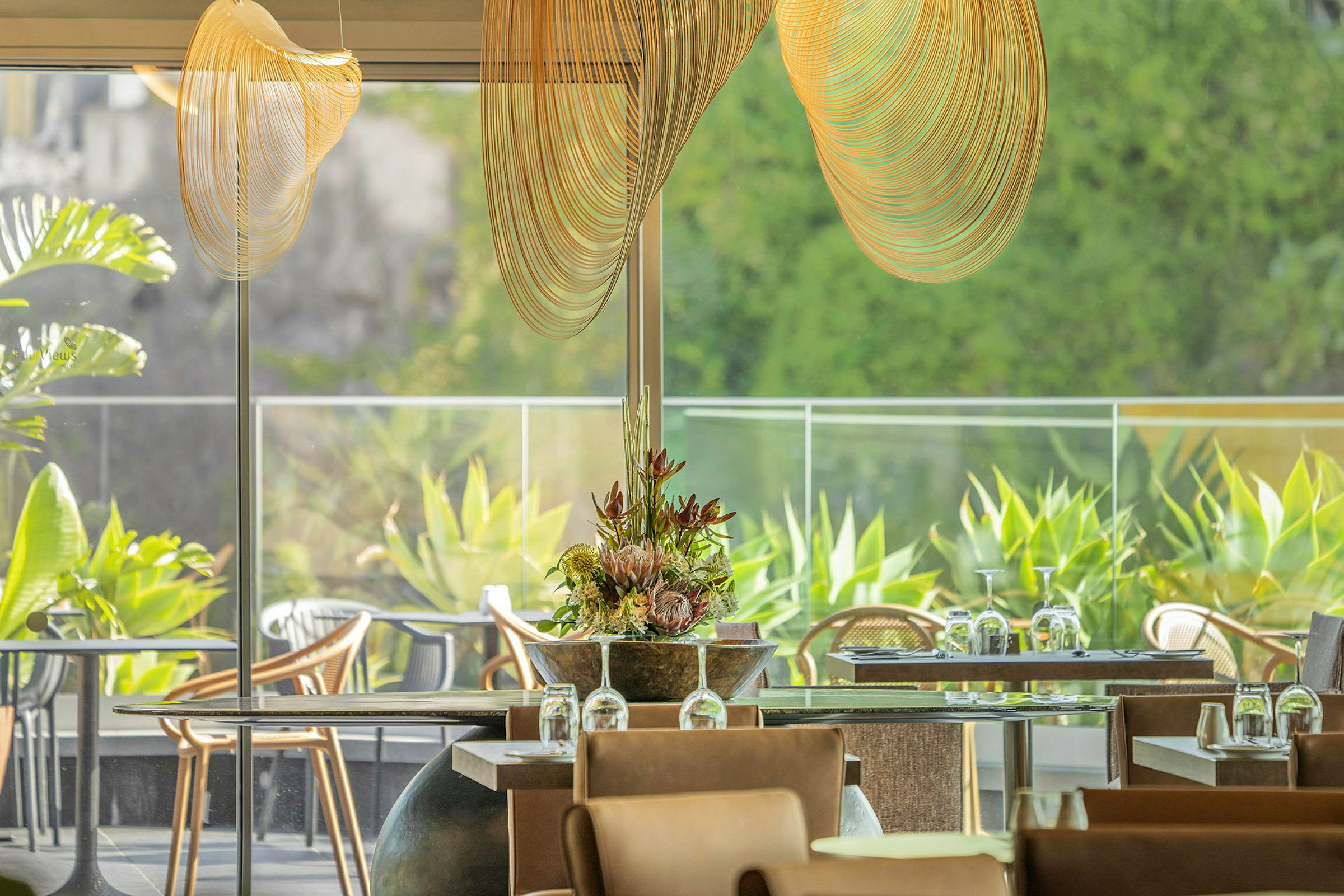 Et lyst og luftig innredet restaurantrom med glass og grønne planter. (AI-generert tekst)