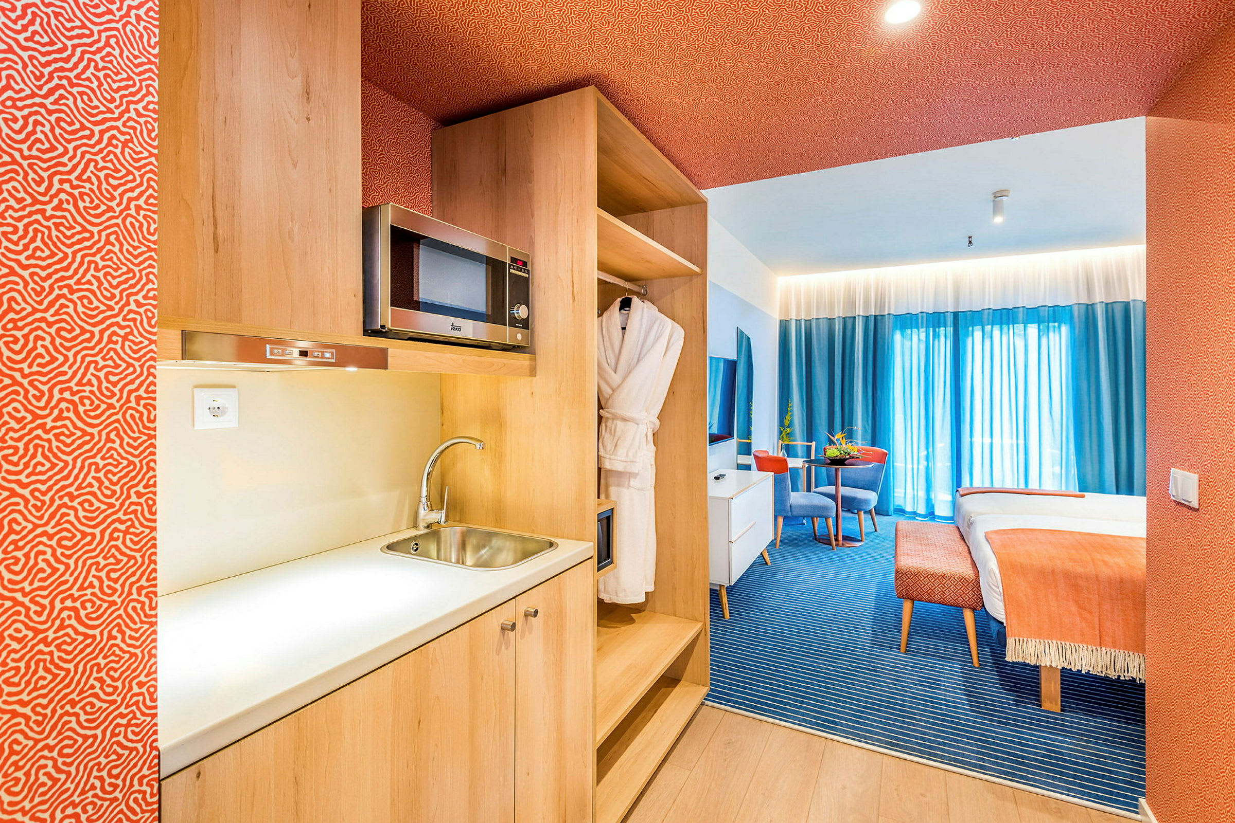 En hotellsuite med kjøkkenkrok, sittegruppe og seng. (AI-generert tekst)