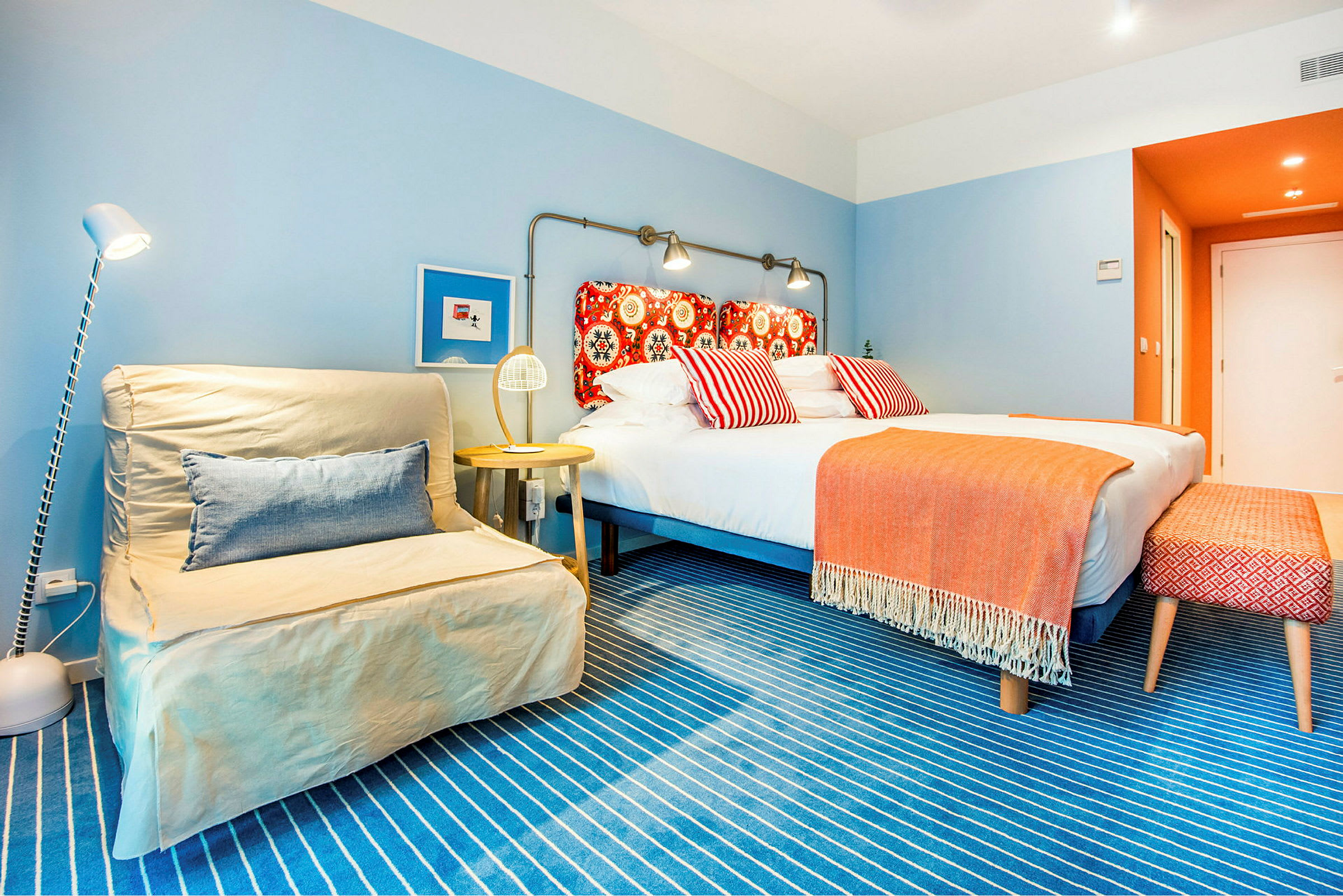 Et fargerikt hotellrom med en dobbeltseng og dekorative puter. (AI-generert tekst)
