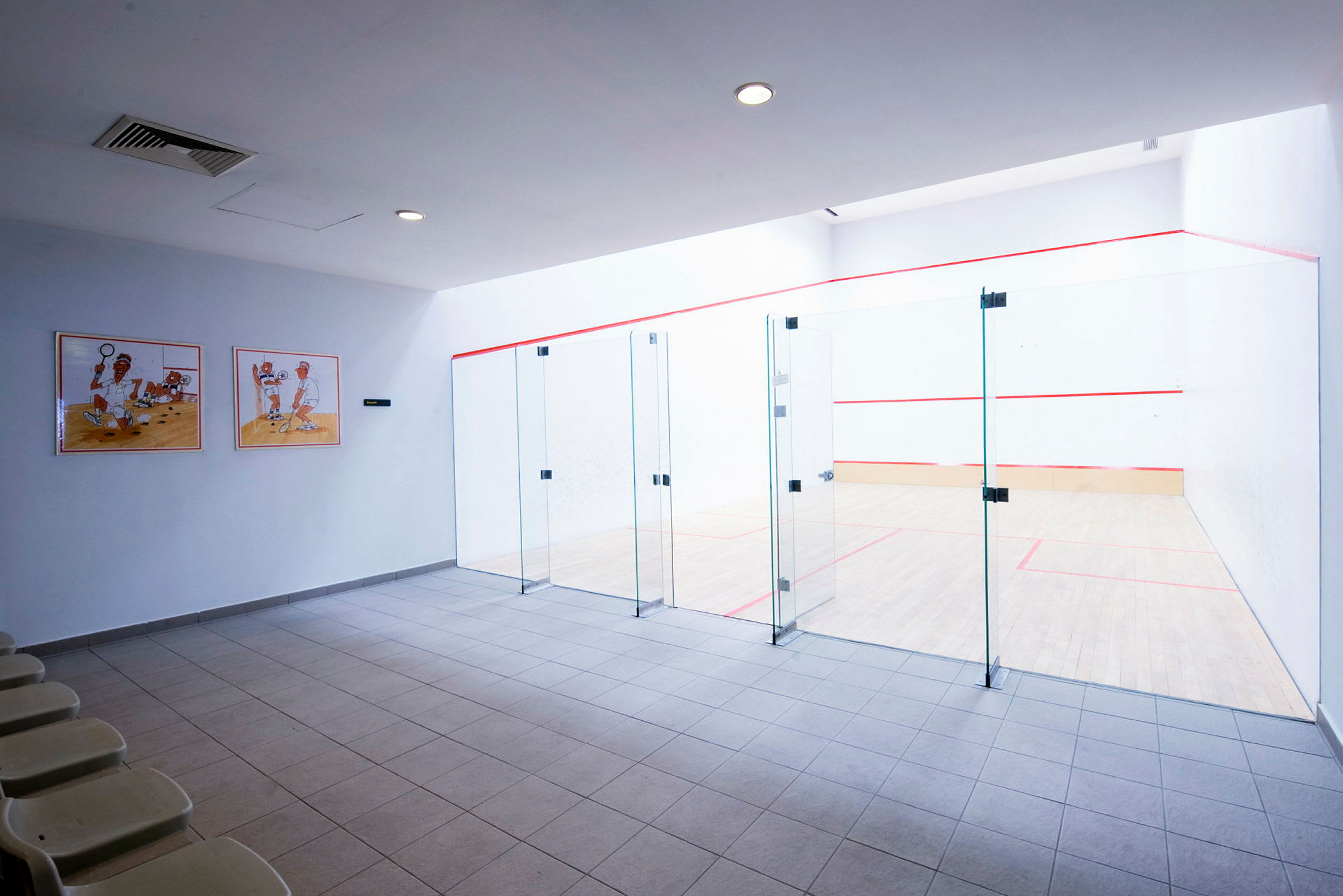 Bilde av en squashhall med glassvegger og sitteplasser. (AI-generert tekst)