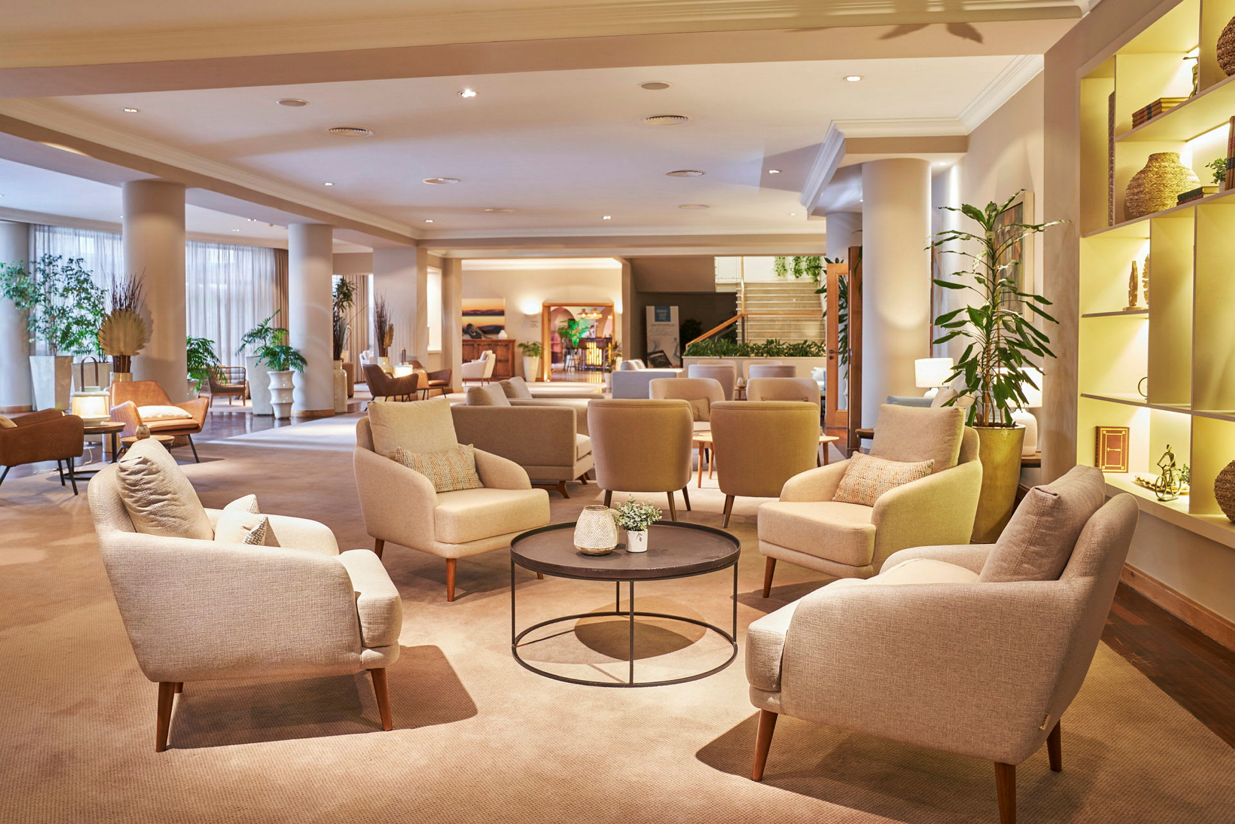 En hotellobby med komfortable stoler og sofaer, bord med dekorasjoner og planter. (AI-generert tekst)
