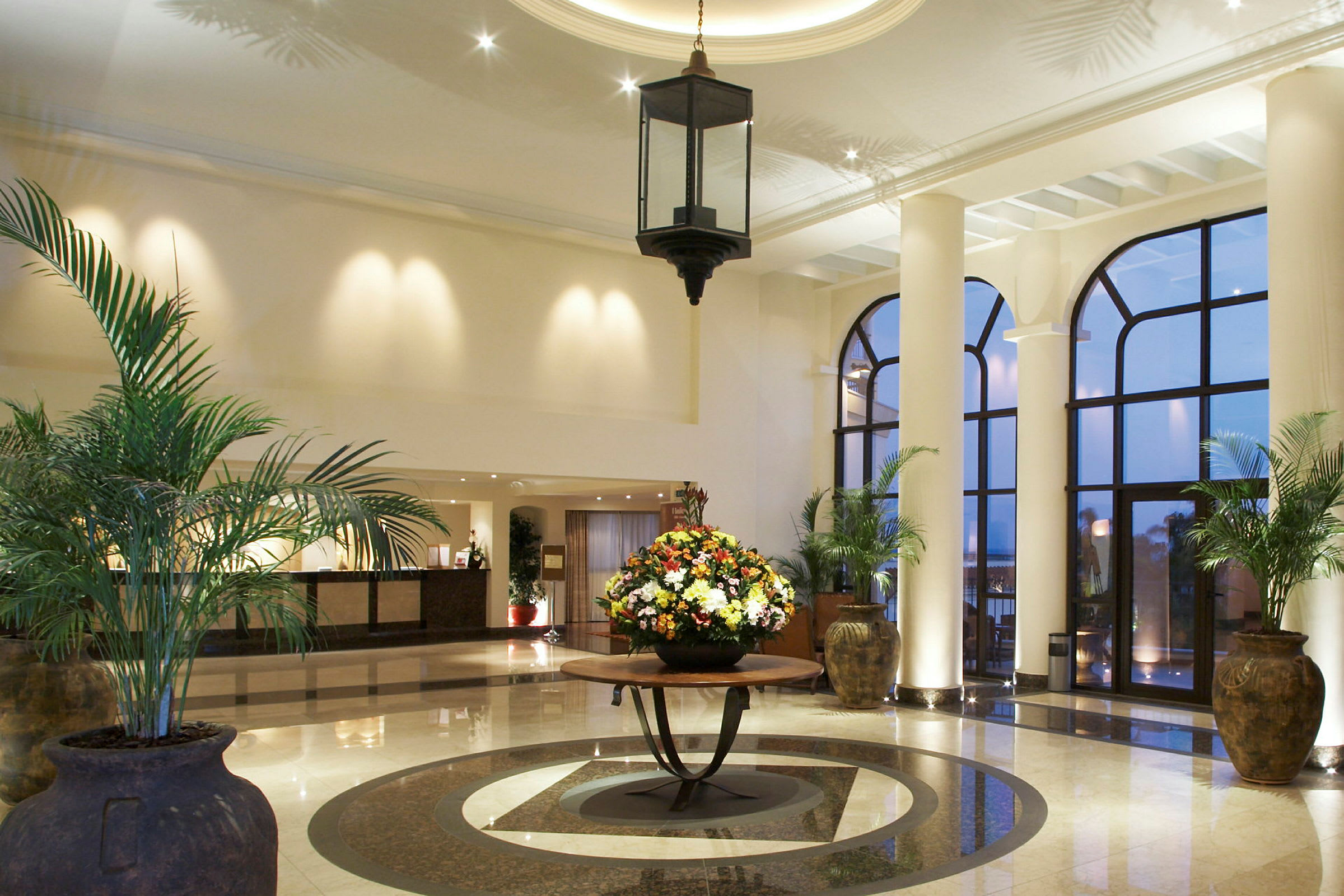 Hotellobby med store vinduer og dekorative planter. (AI-generert tekst)