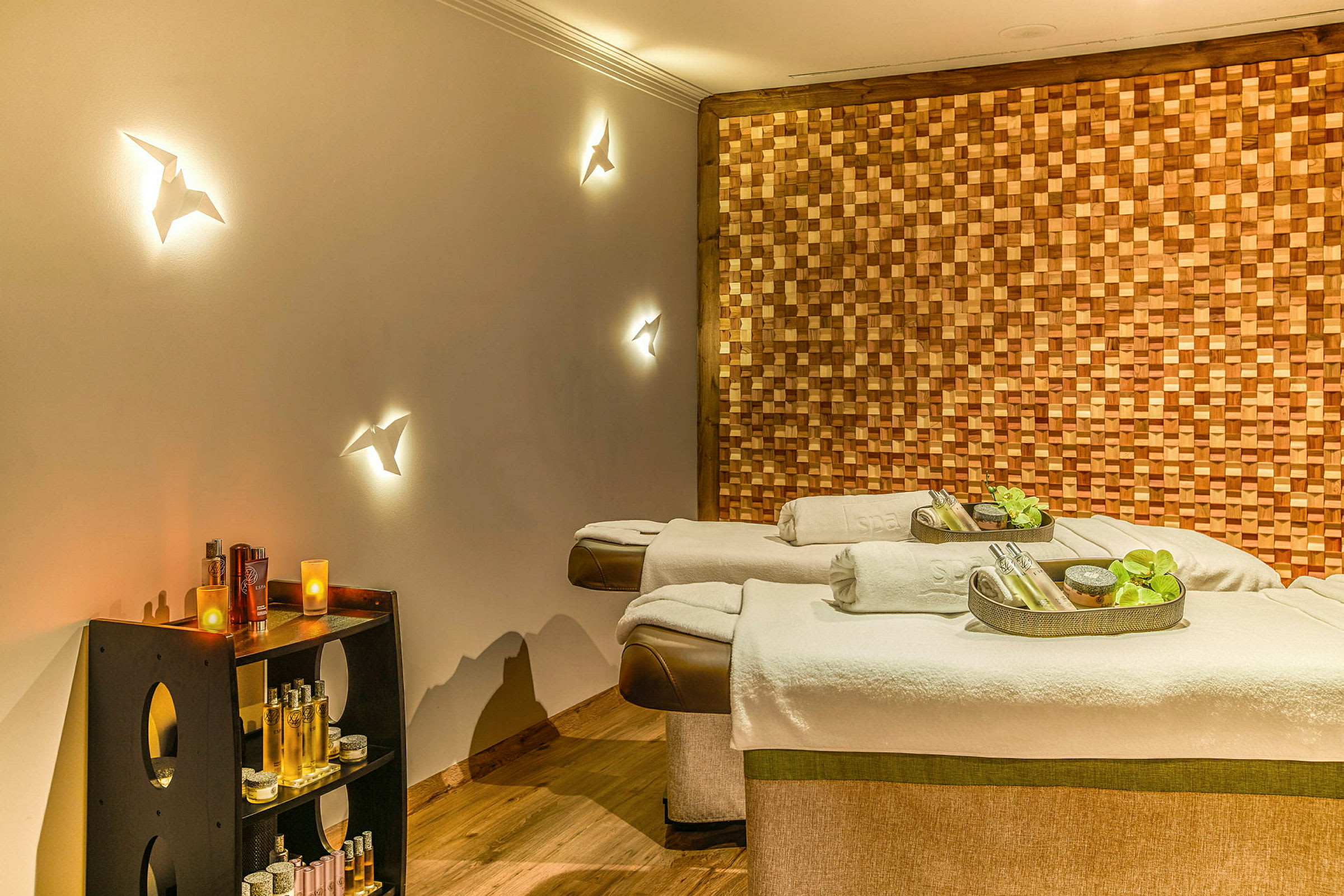 To spa-massasjebord med dekorative tilbehør, omgitt av en veggpanel i tre og hyller med forskjellige spa-produkter. (AI-generert tekst)