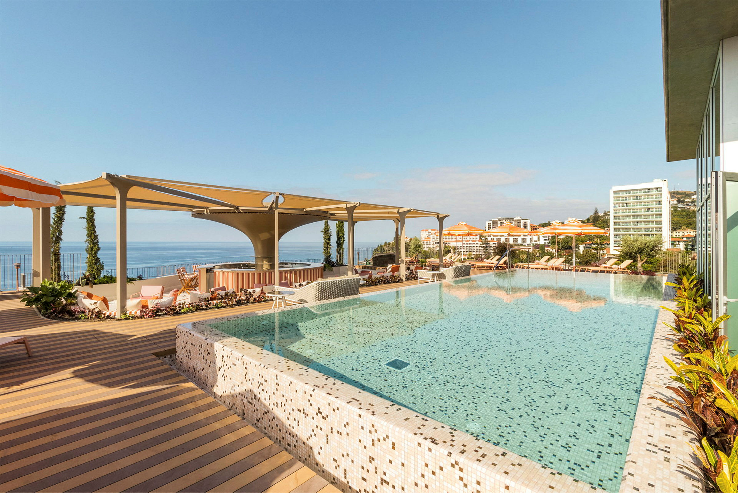 Et infinity-basseng med utsikt over havet og hotellbygninger i bakgrunnen. (AI-generert tekst)