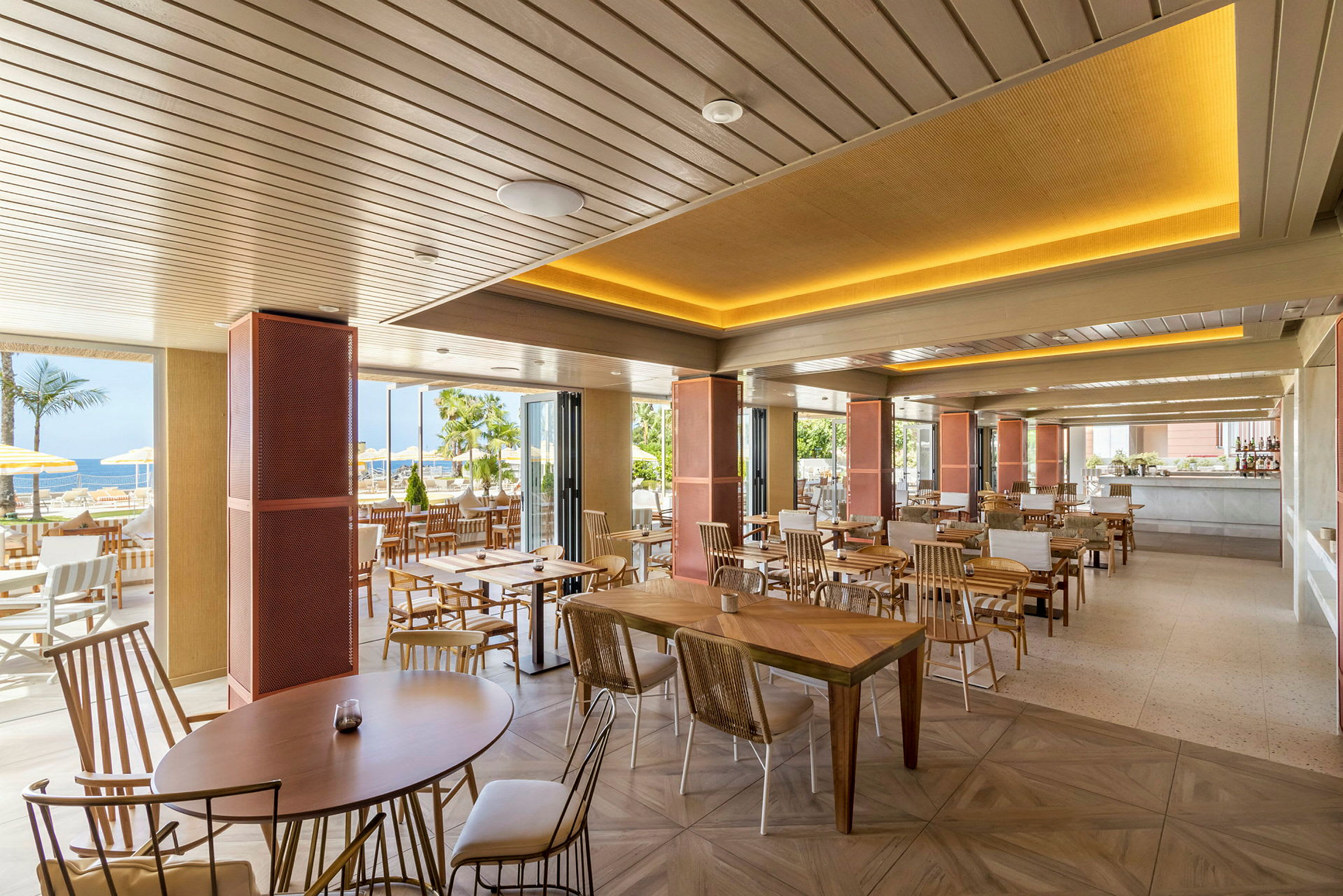 En moderne restaurant med trebord og stoler, åpen mot et utendørsmiljø med palmer. (AI-generert tekst)