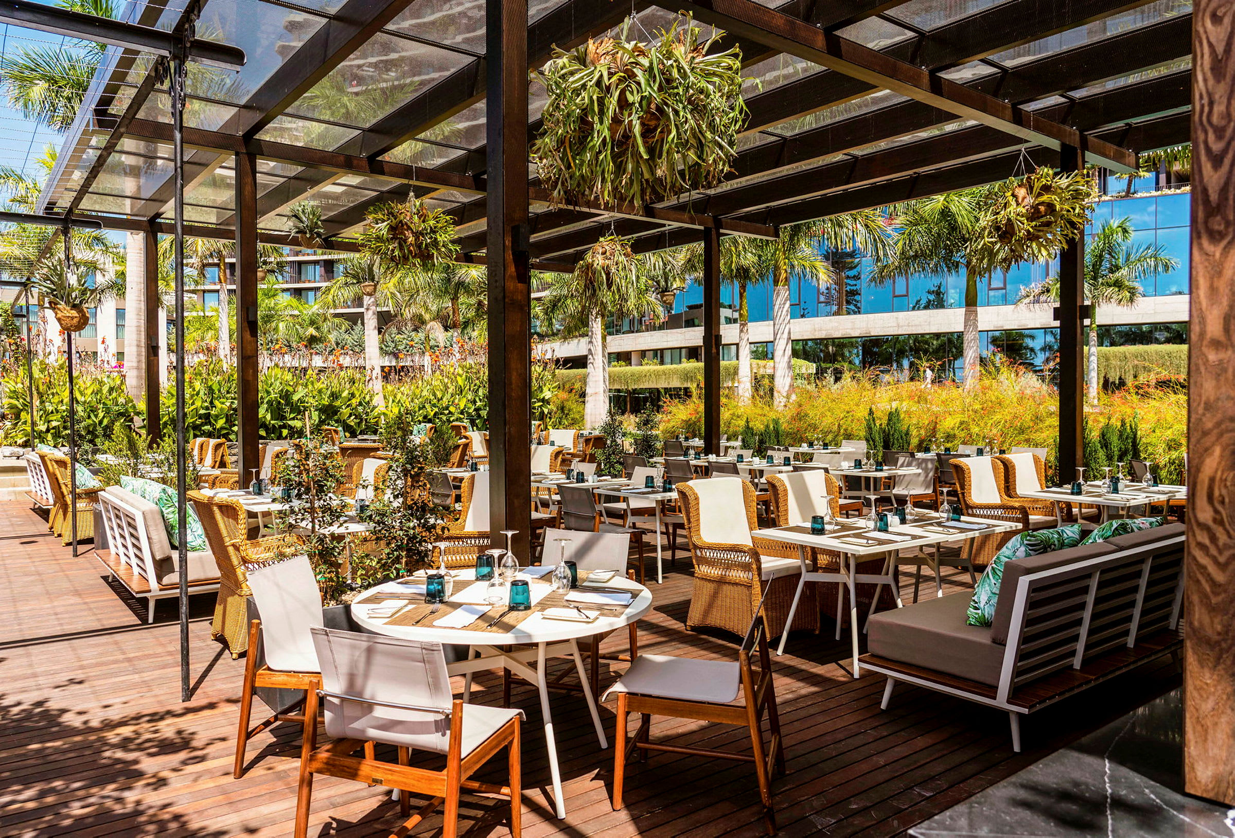 Utendørsrestaurant med trebord og stoler under en pergola. (AI-generert tekst)