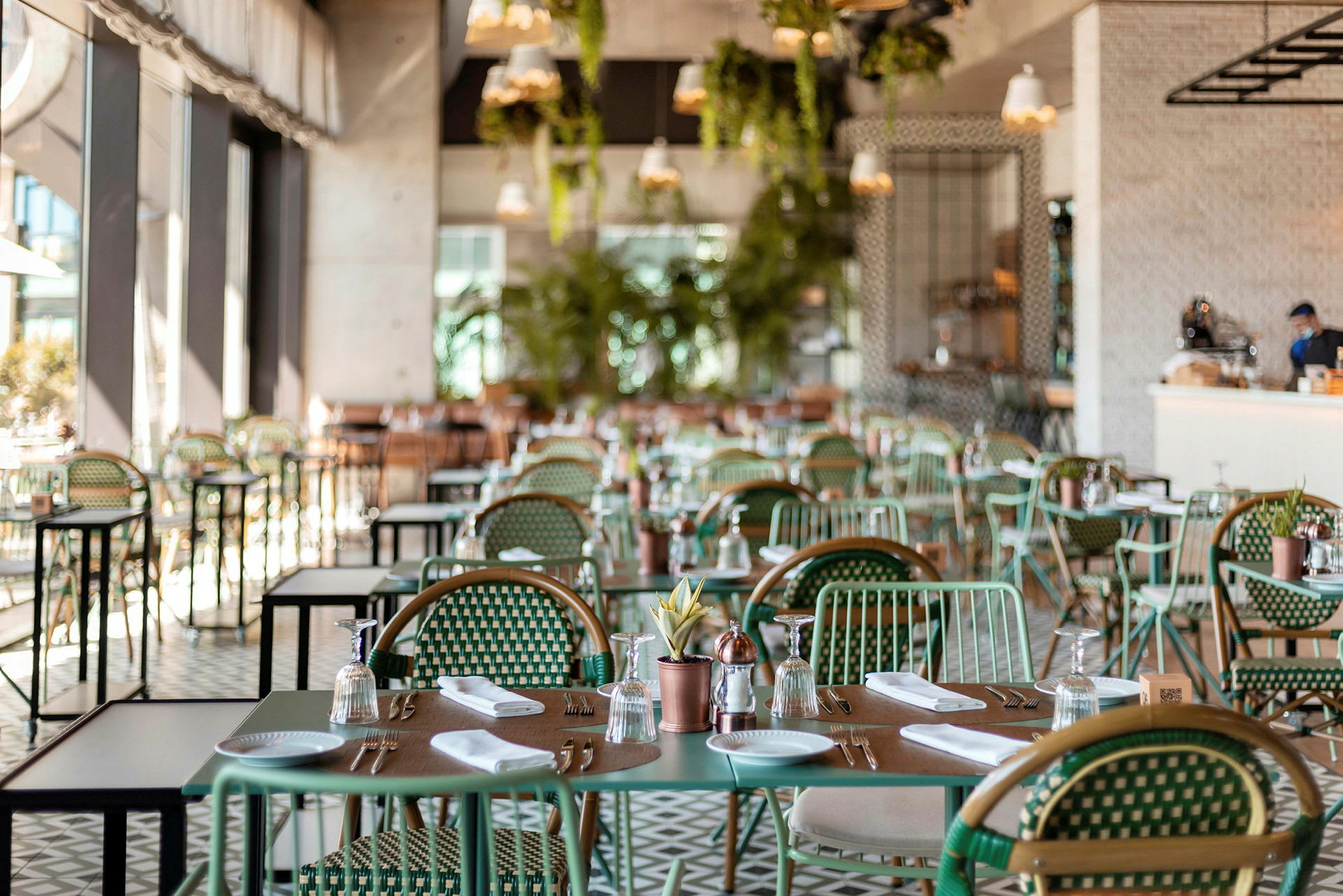 Interiør av en restaurant med dekkede bord og stoler. (AI-generert tekst)