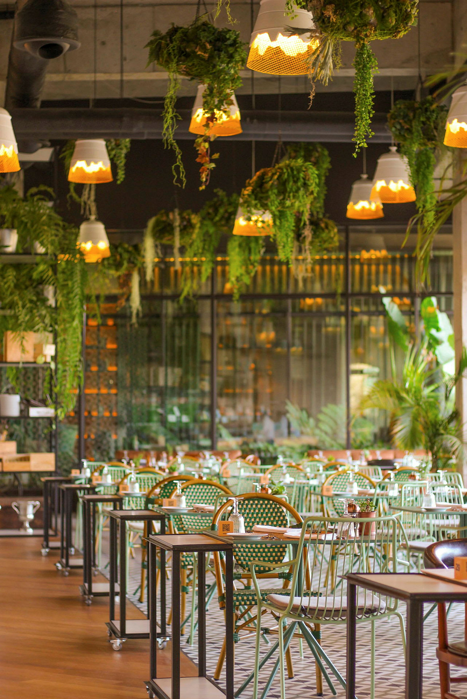 Interiør av en restaurant med grønne sitteplasser og planter i taket. (AI-generert tekst)