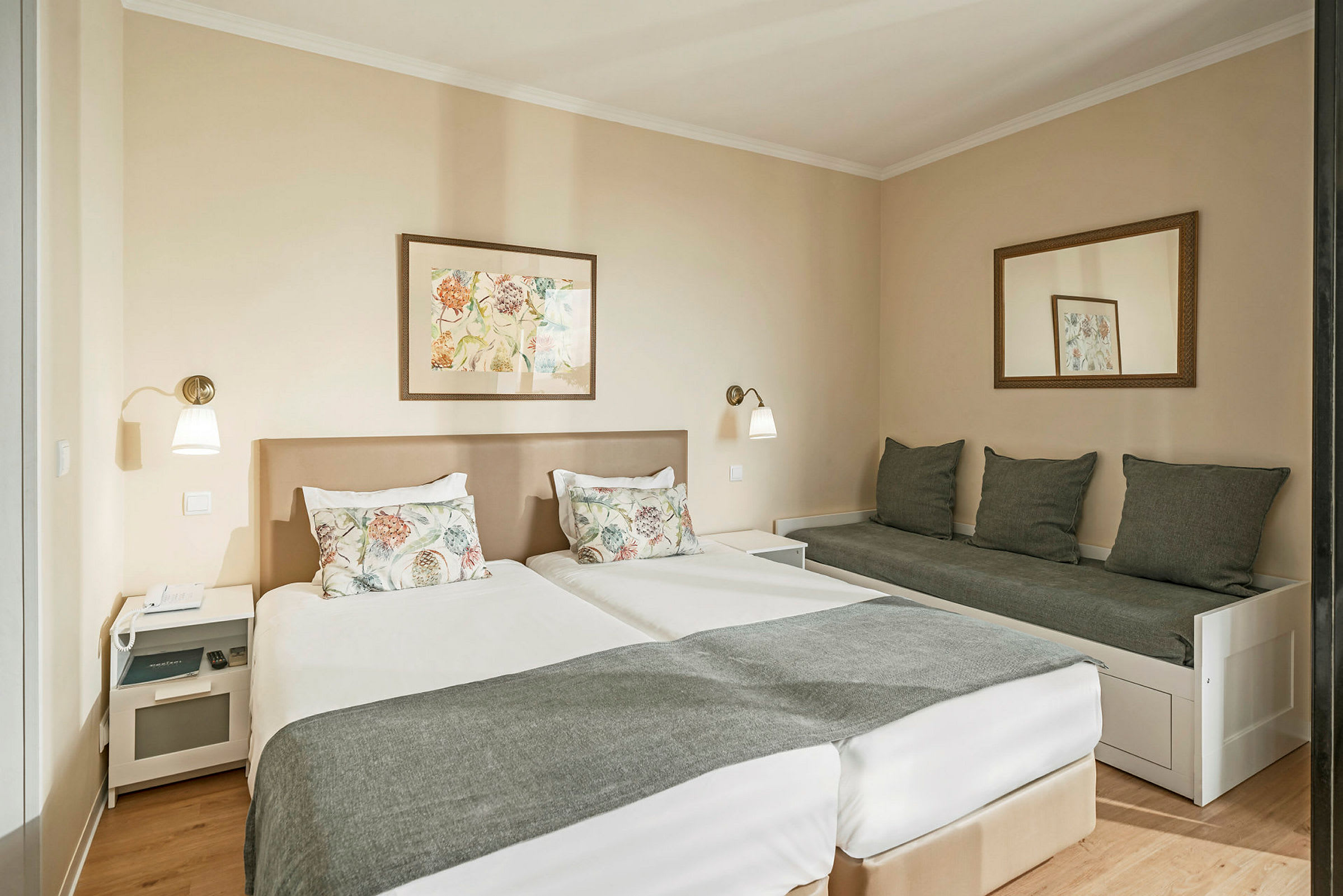 Et hotellrom med to senger og en sofa ved siden av. (AI-generert tekst)
