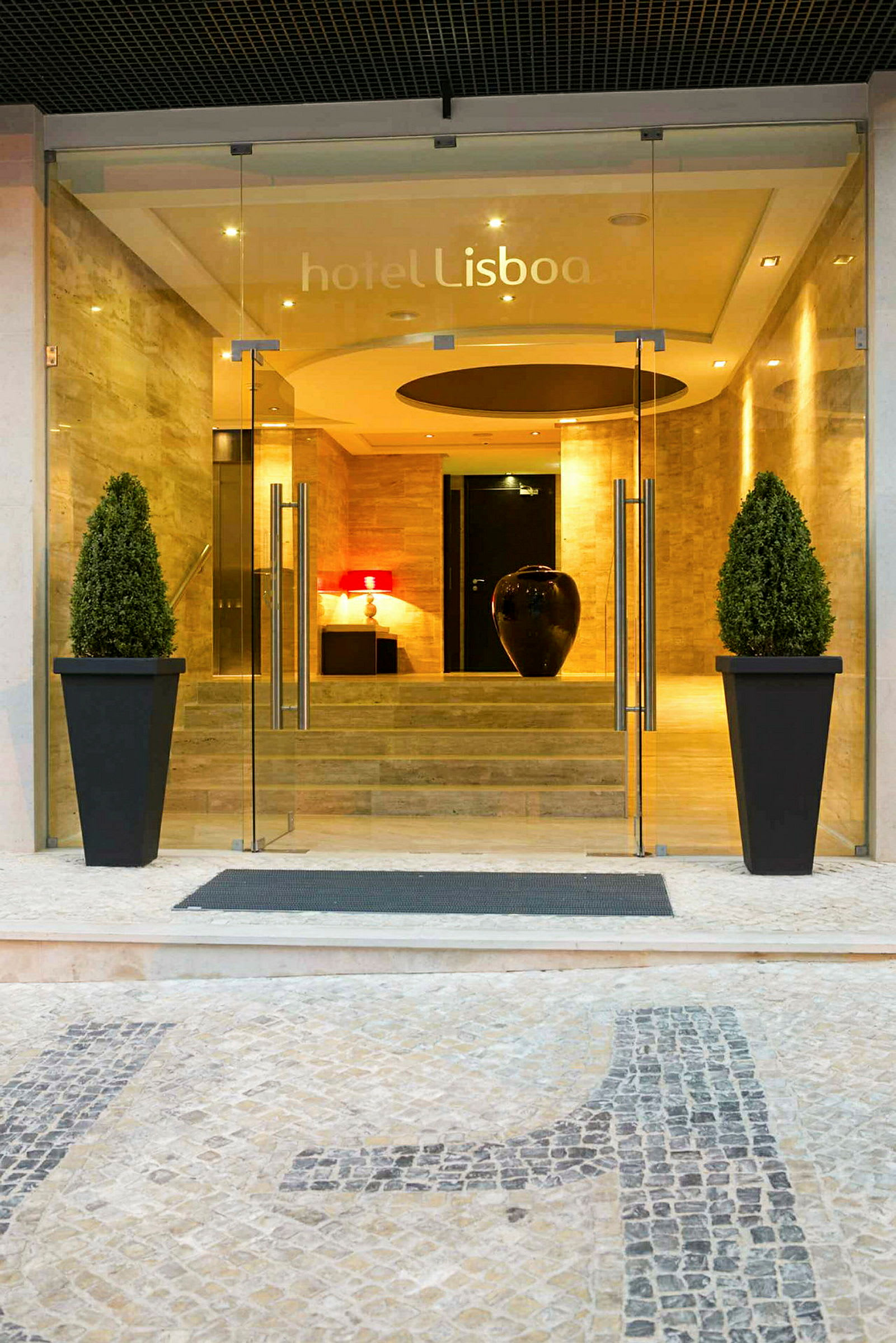 Inngangen til hotellet Lisboa med glassdører og dekorasjoner. (AI-generert tekst)