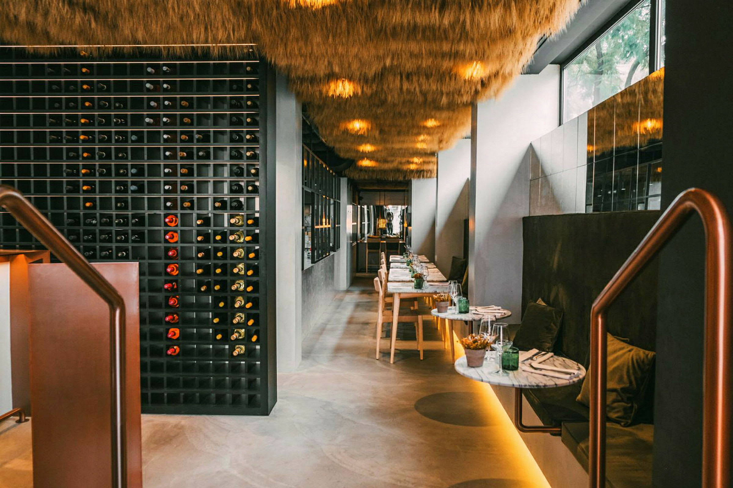 Restaurantinteriør med en vinvegg, bord og sitteplasser. (AI-generert tekst)