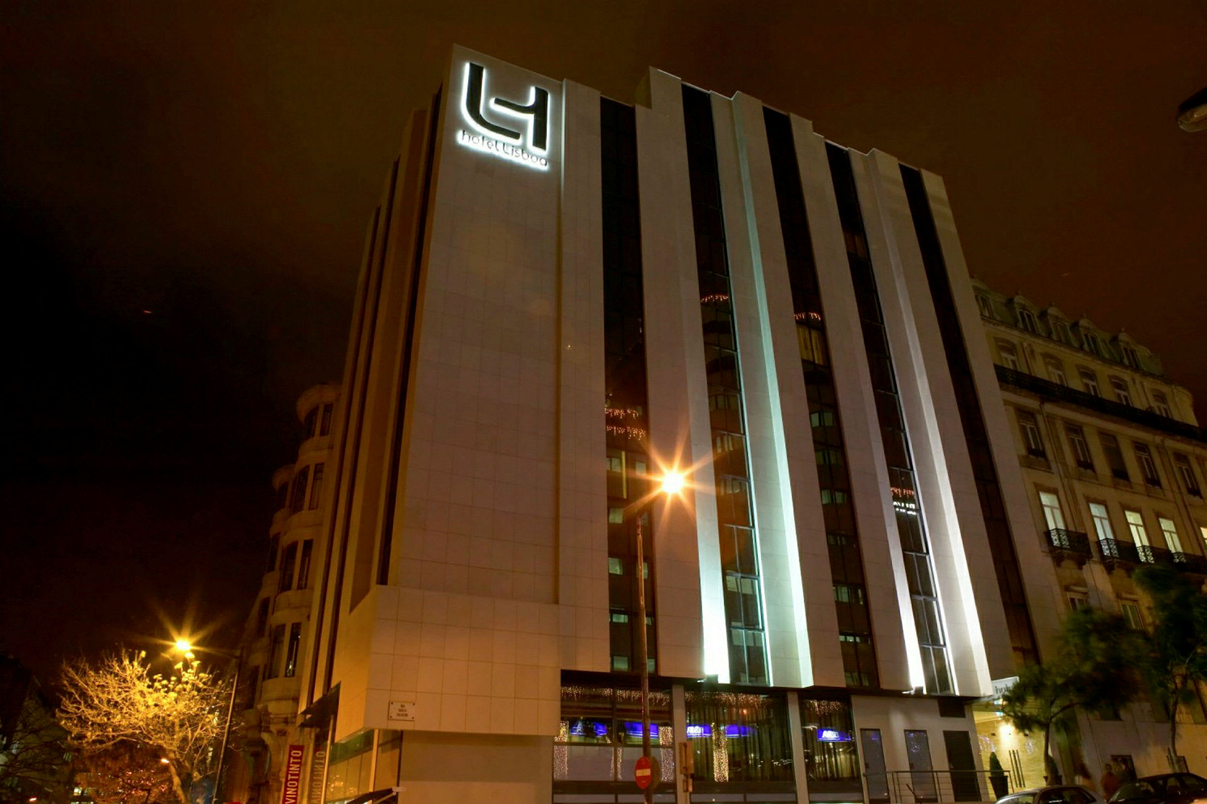 Et hotell med moderne ytre fotografert om natten. Bygningens fasade er belyst. (AI-generert tekst)