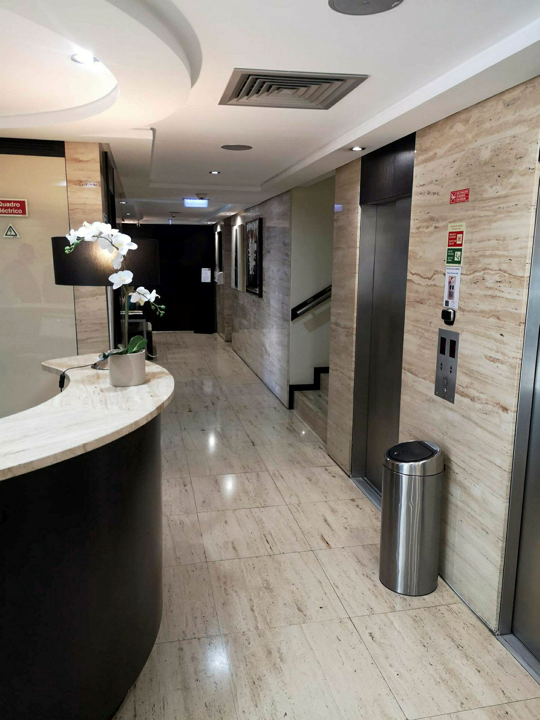 En moderne hotellkorridor med heis og concierge-resepsjon. (AI-generert tekst)