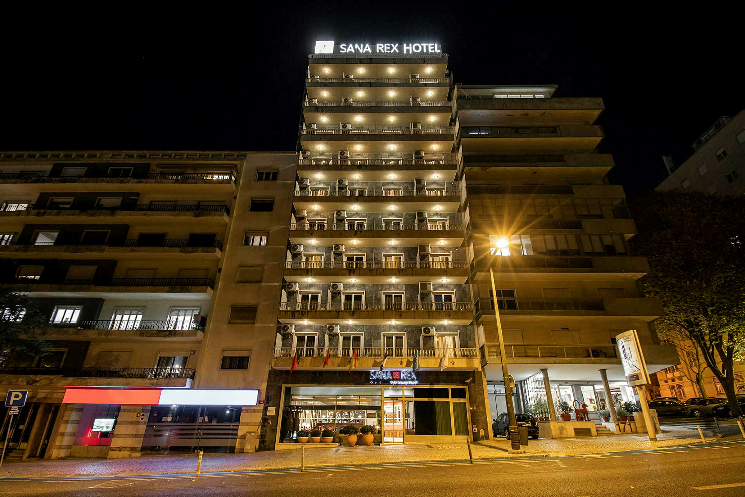 Bilde av hotellet Sana Rex Hotel om natten, med fasaden opplyst. (AI-generert tekst)