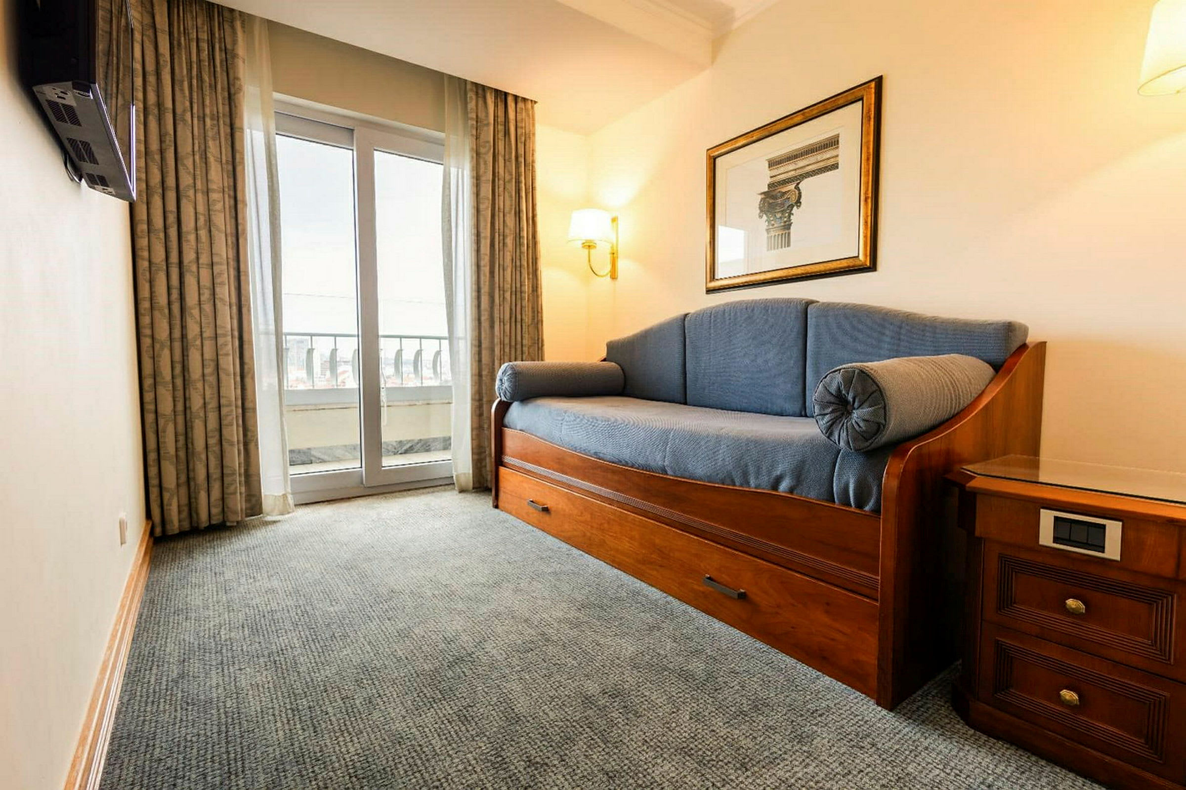 Et rom med en sofaseng, et nattbord og en balkongdør. (AI-generert tekst)