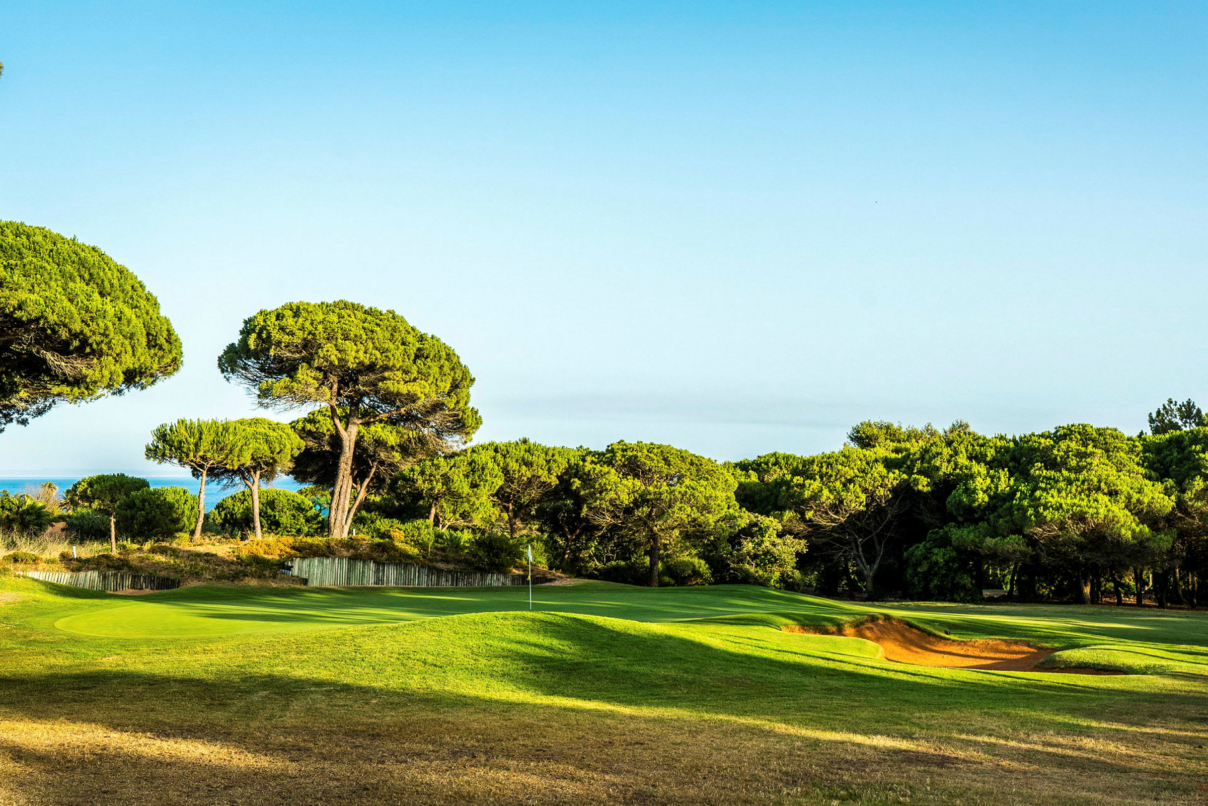 Bilde av en golfbane med grønt gress og omkringliggende trær. (AI-generert tekst)