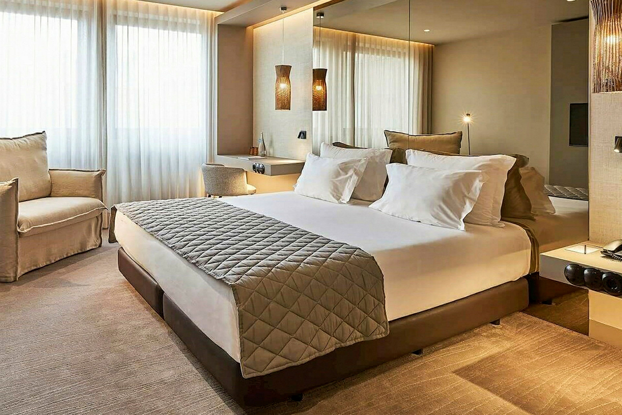 Et moderne hotellrom med en dobbeltseng, to stoler og et skrivebord. (AI-generert tekst)