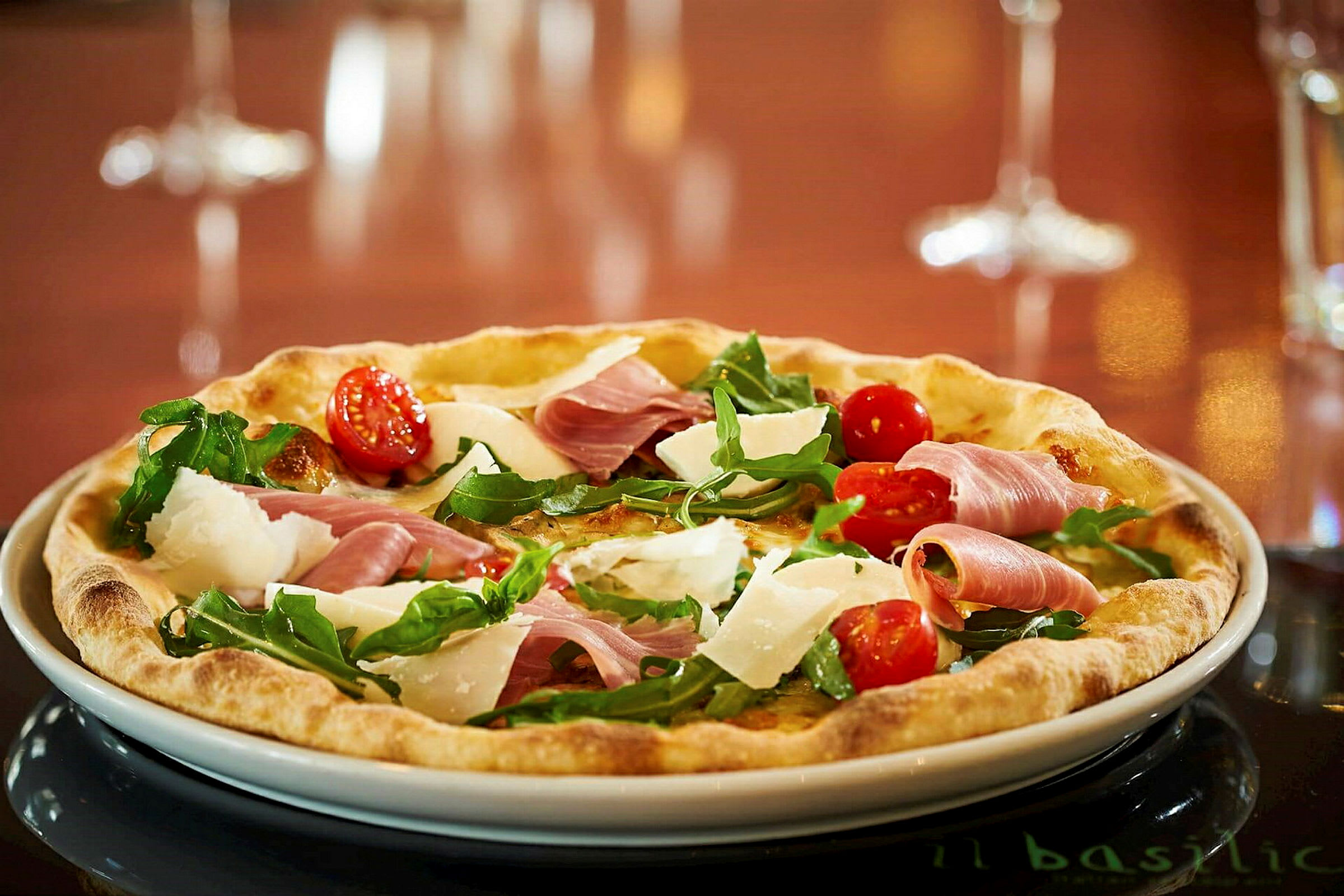 En pizza med cherrytomater, ruccola, parmesan og skinke. (AI-generert tekst)