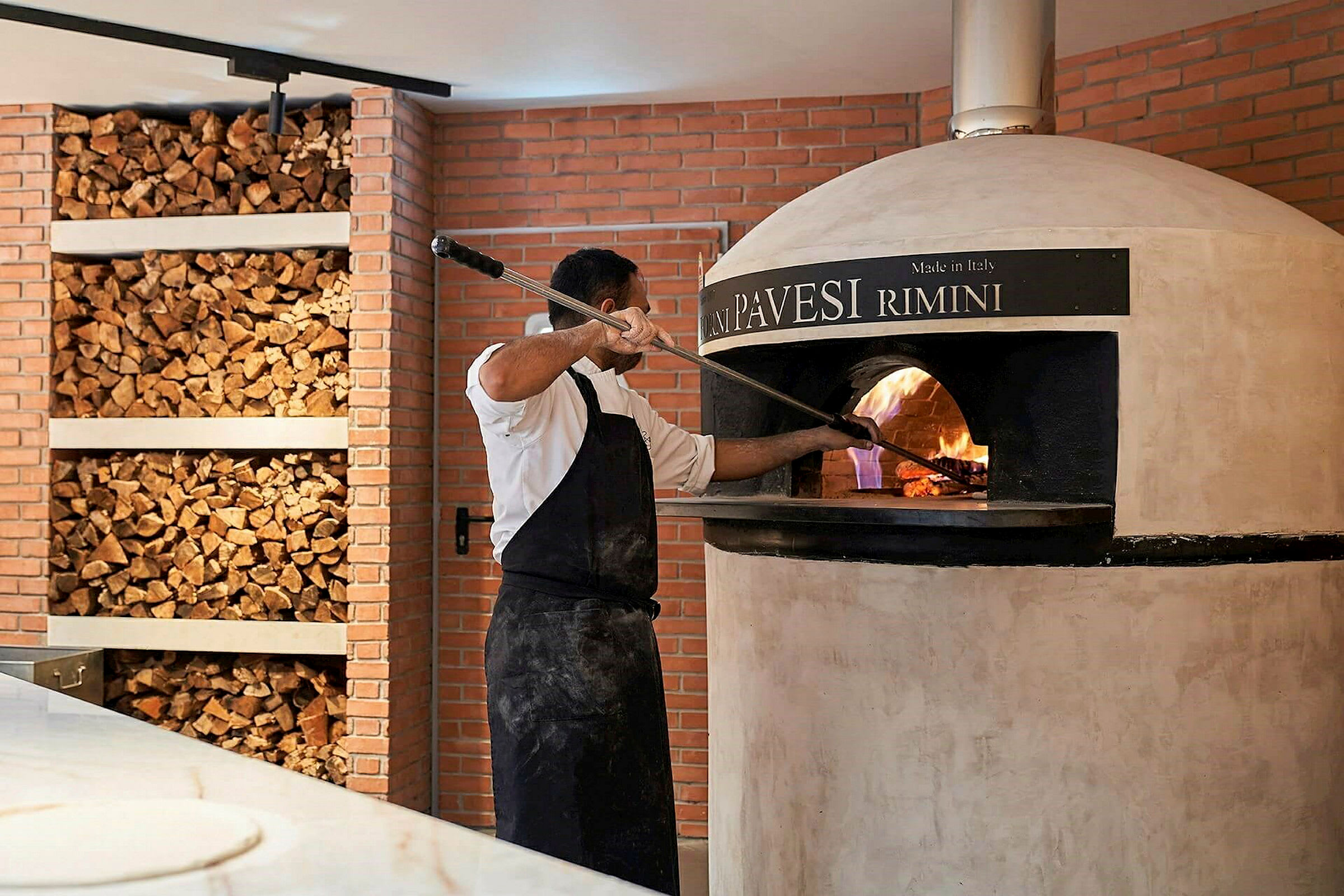 Personen lager pizza i vedfyrt ovn. (AI-generert tekst)