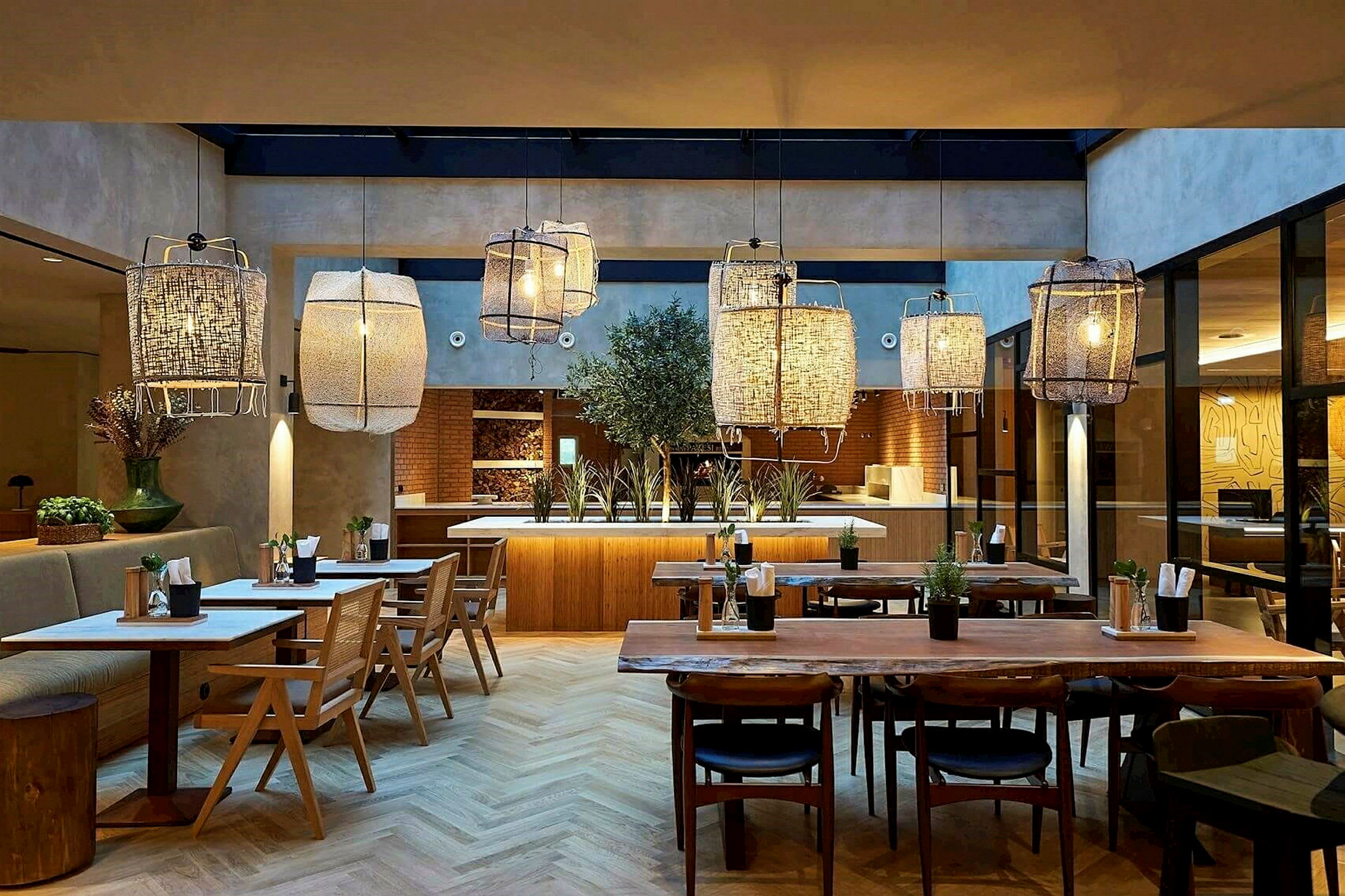 Interiør av en restaurant med trebord, stoler og store hengende lamper. (AI-generert tekst)