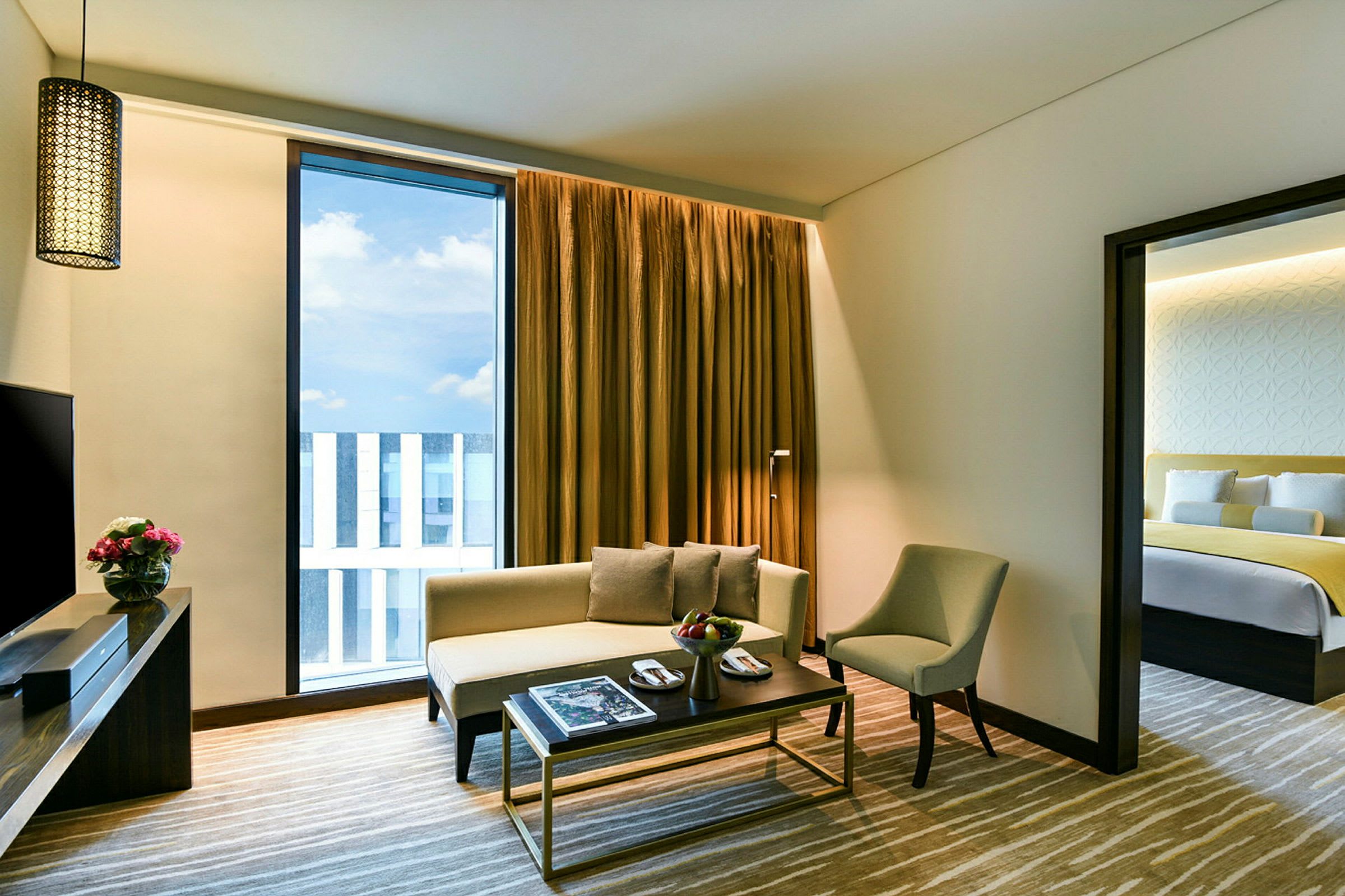 Et moderne og lyst hotellrom med en stue og en dør som fører til et soverom. (AI-generert tekst)