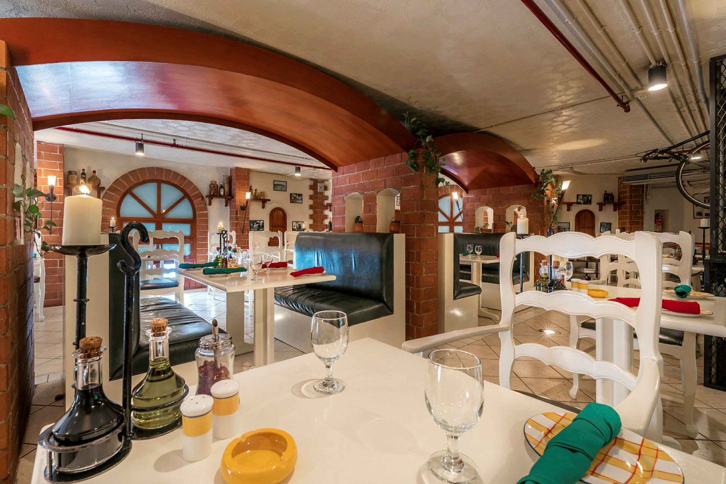 En interiør av en restaurant med hvite bord, stoler og mursteinsvegger. (AI-generert tekst)