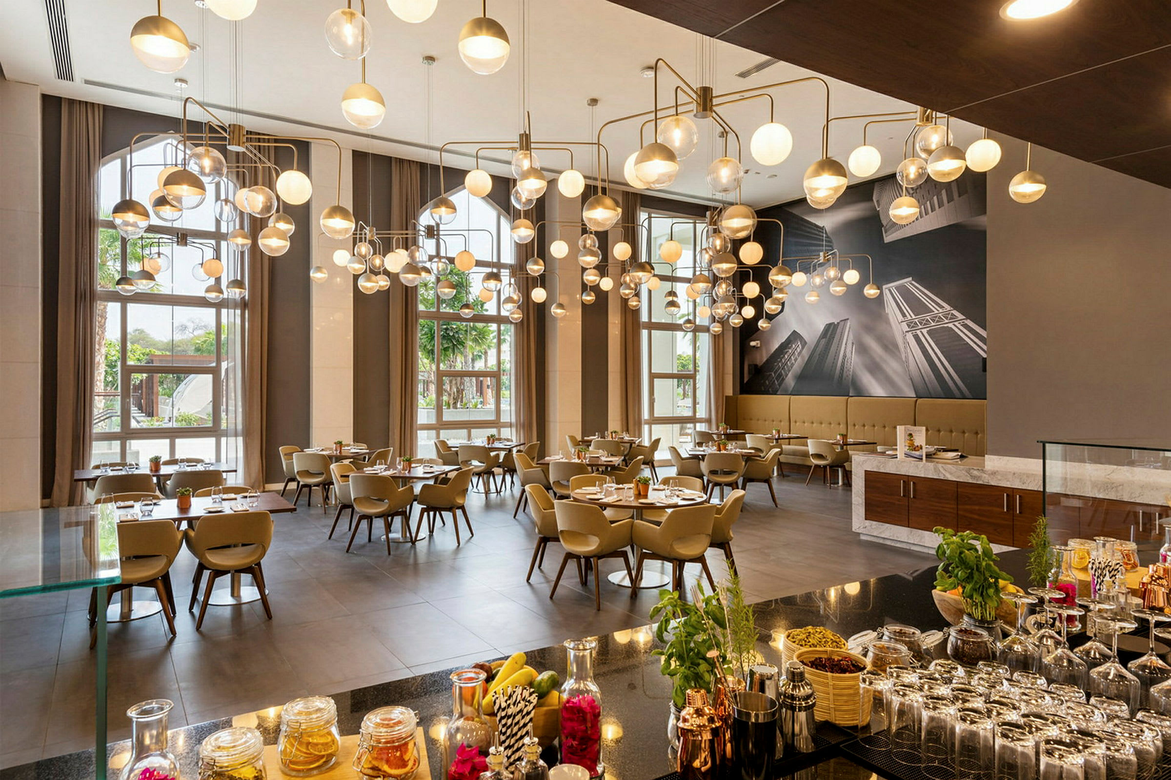 En elegant restaurant med moderne hengende lamper, dekkede bord og store vinduer som slipper inn naturlig lys. (AI-generert tekst)
