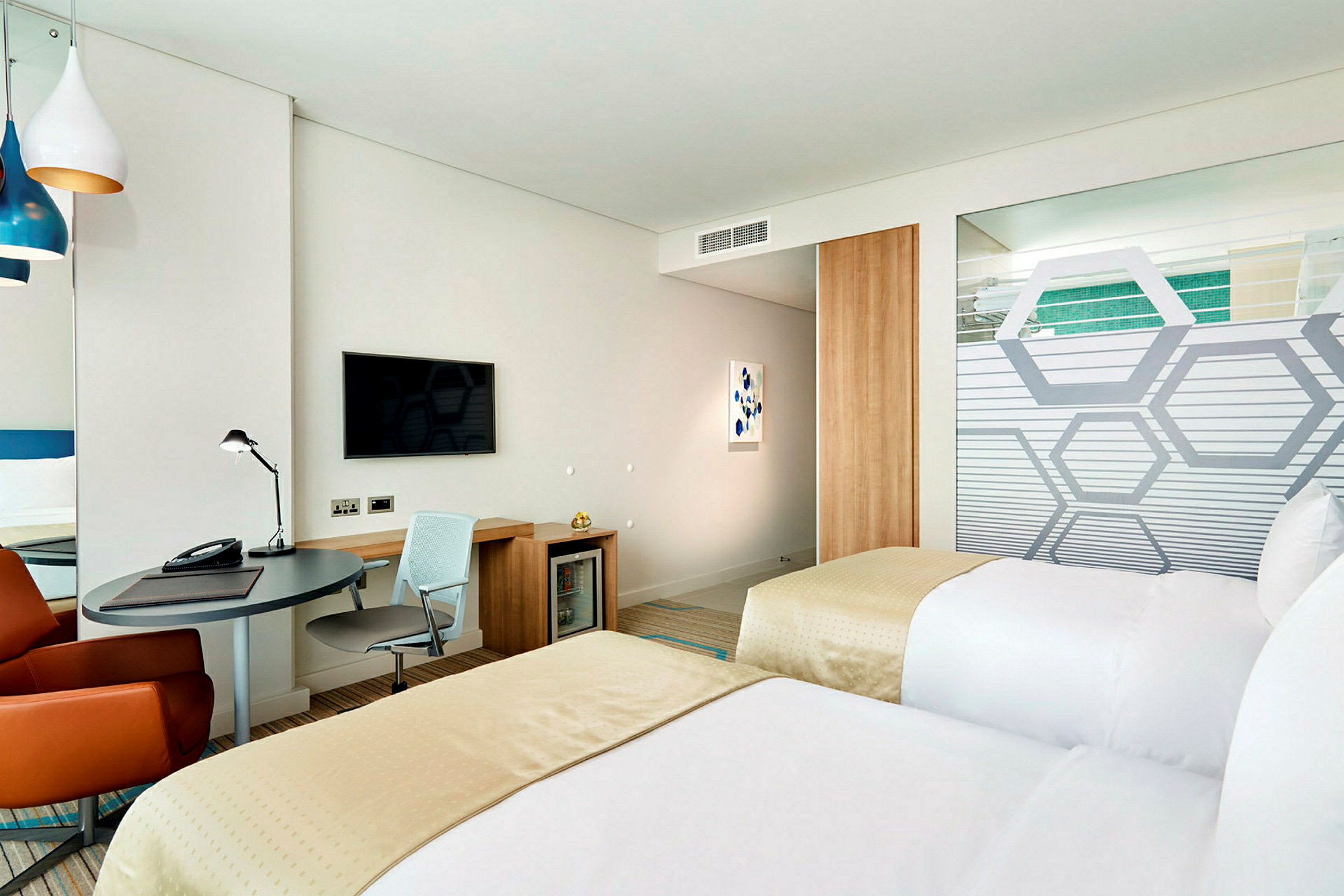 Hotellrom med to enkeltsenger, skrivebord og vegg-TV. (AI-generert tekst)