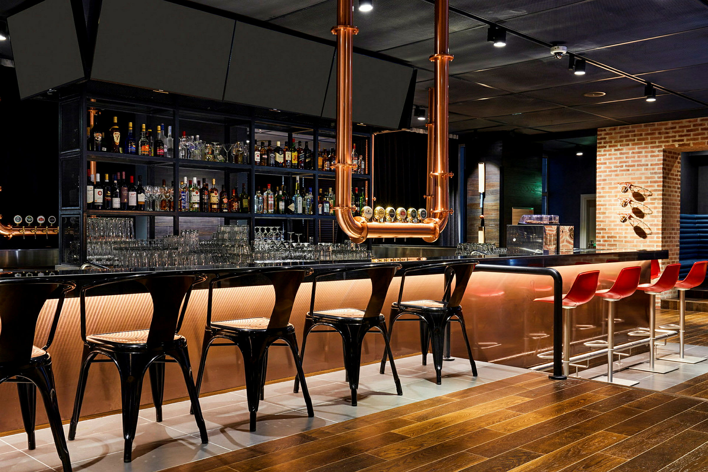 En moderne bar med en lang bardisk, høye stoler og flasker plassert på hyller bak. (AI-generert tekst)