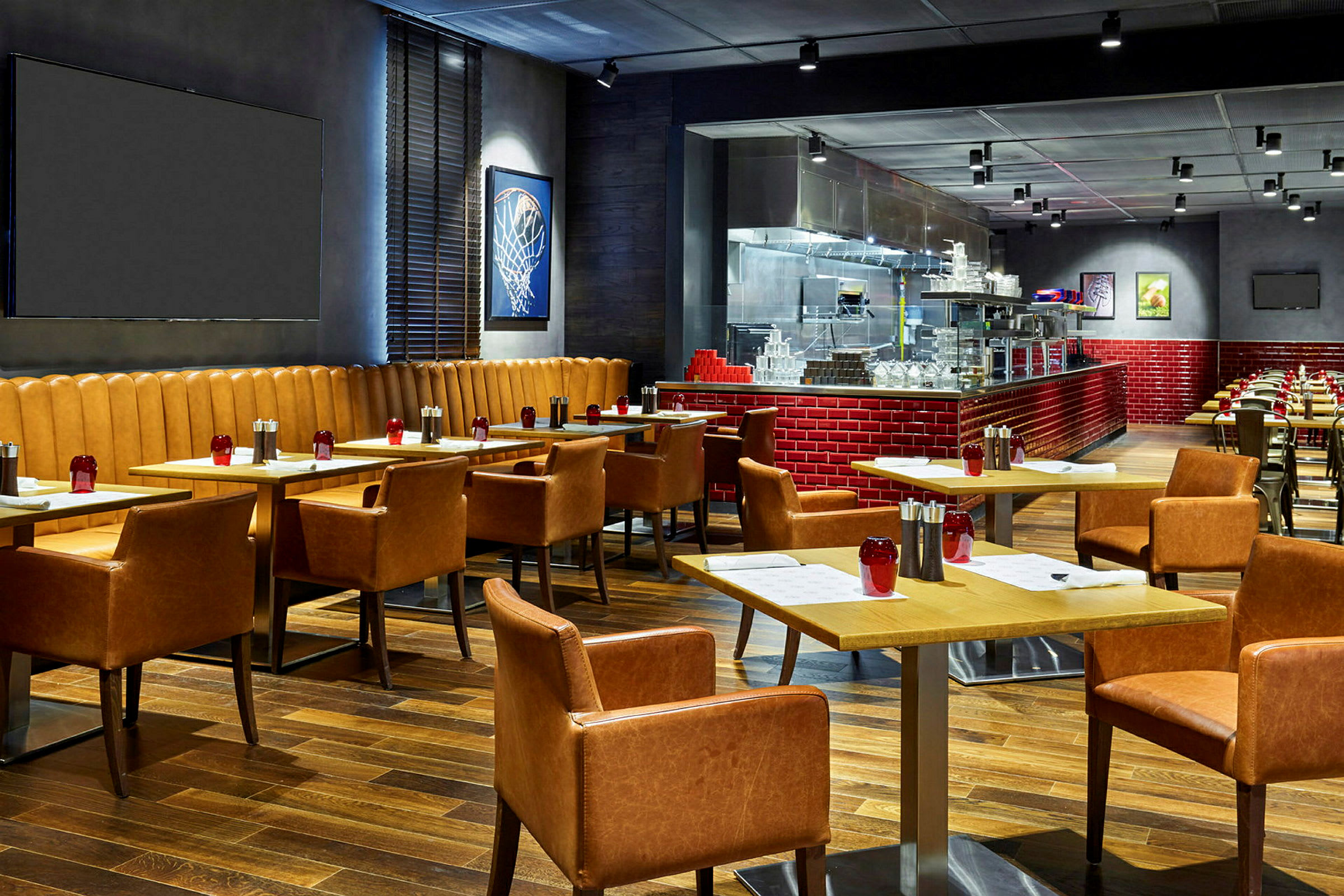 En moderne restaurant med trebord og komfortable lærstoler. Veggene dekorert med kunst og åpent kjøkken med røde fliser. (AI-generert tekst)