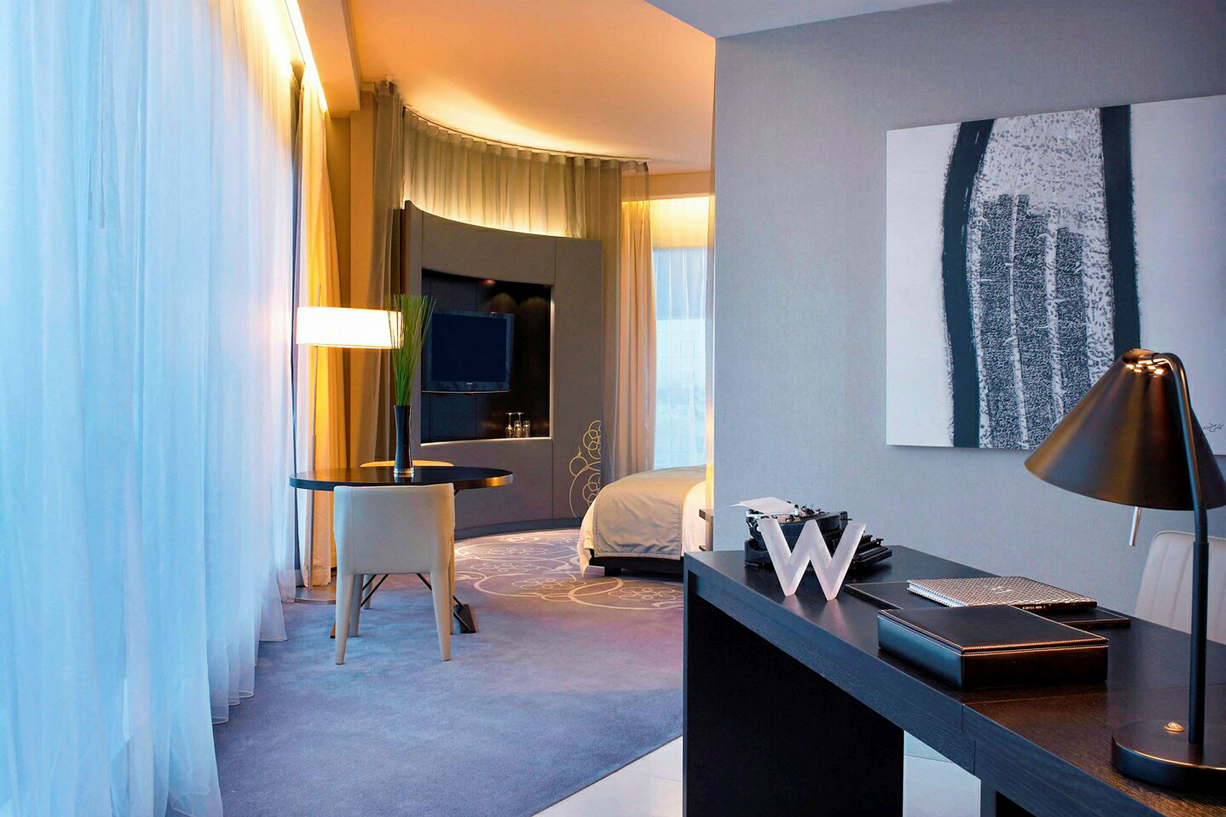 Moderne innredet hotellrom med skrivebordslampe, bord og TV. (AI-generert tekst)