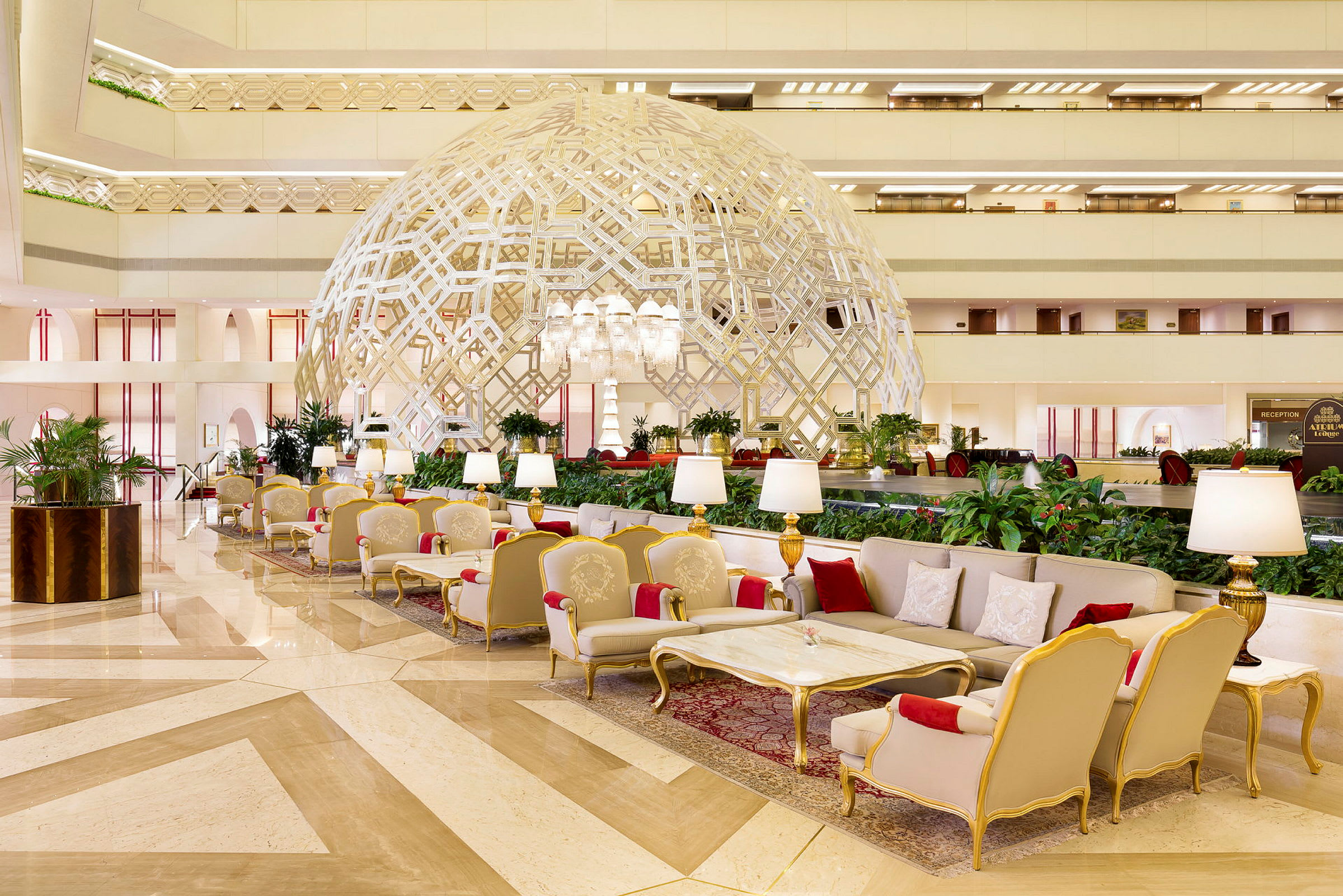 En elegant hotellobby med luksuriøse sitteplasser, en dekorativ geometrisk struktur og velstelte planter. (AI-generert tekst)