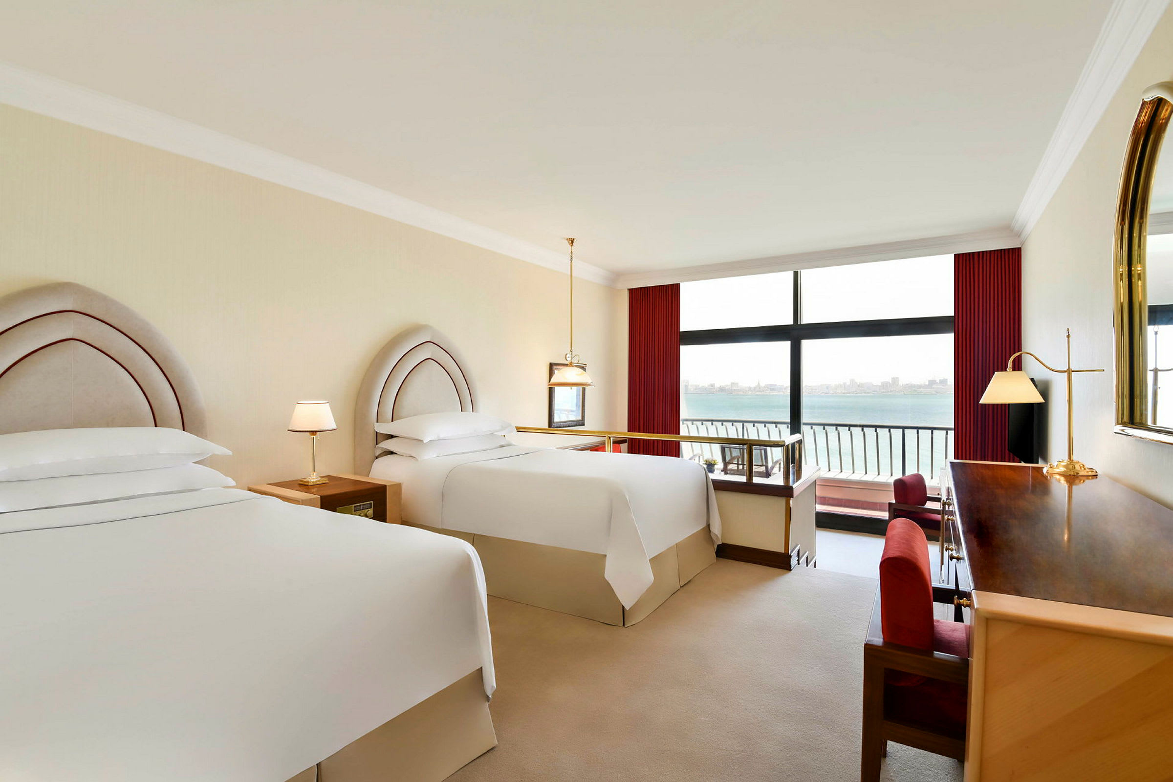 Hotellrom med to senger ved siden av et stort vindu med utsikt over havet. (AI-generert tekst)
