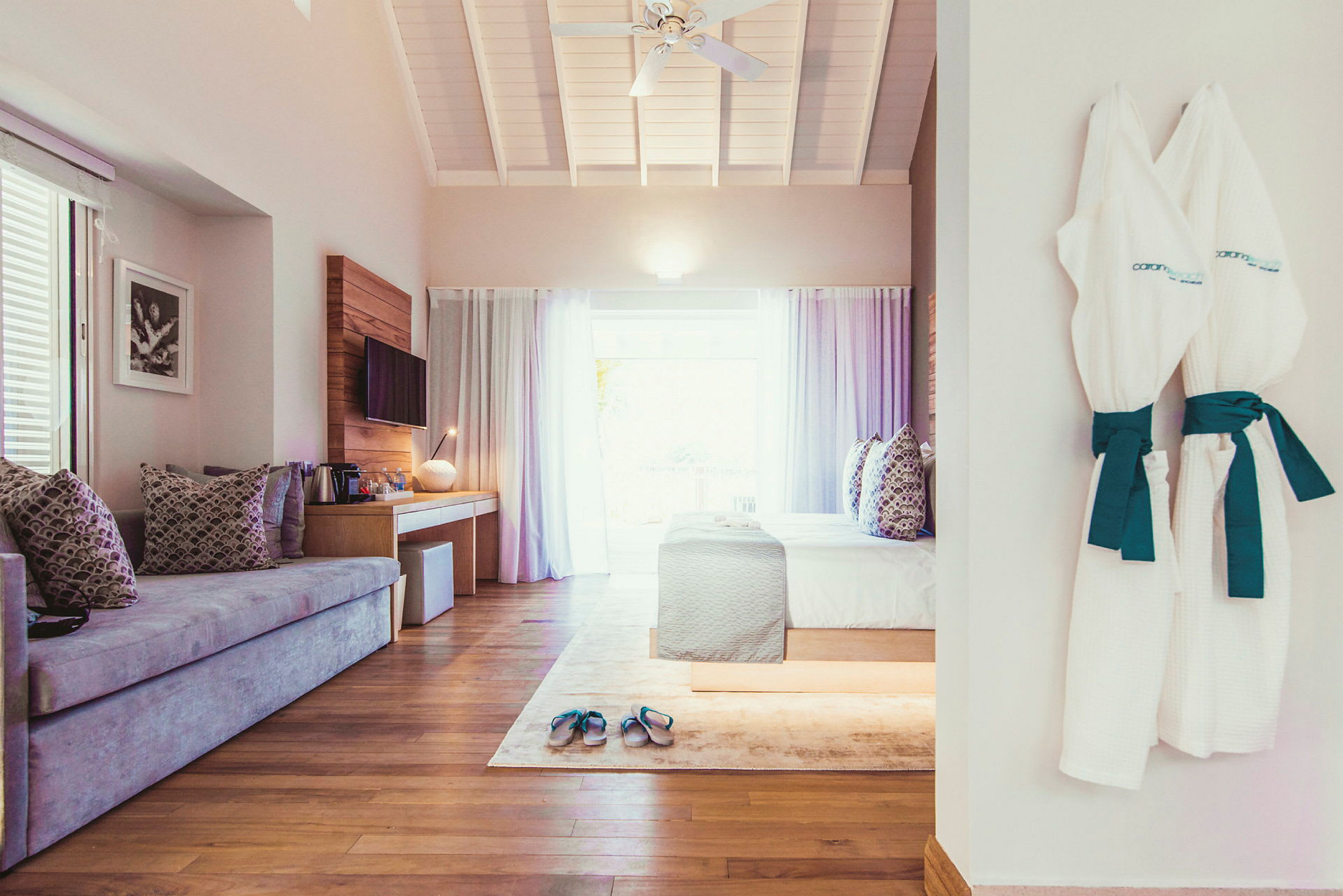 Et hotellrom med sofa, seng og badekåper som henger på veggen. (AI-generert tekst)
