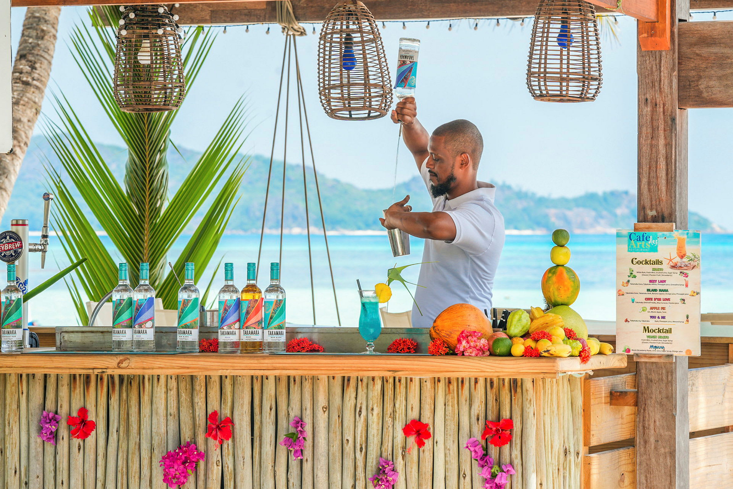 En strandbar dekorert med blomster hvor cocktails blir laget. (AI-generert tekst)