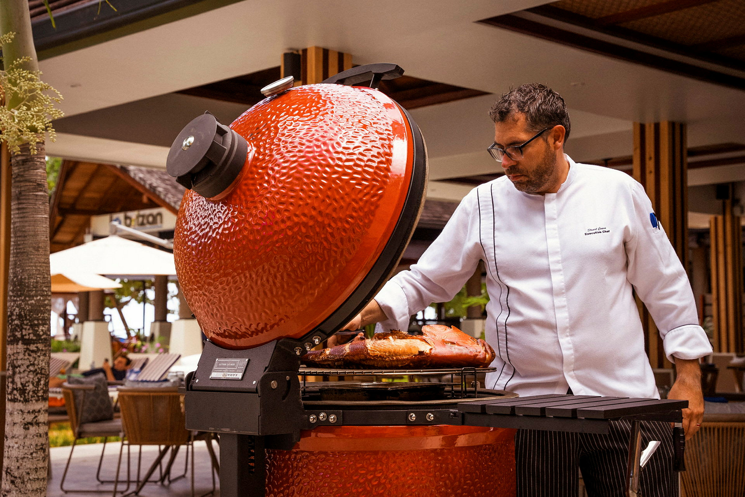 Person ved en åpen rød grill med mat på grillristen. (AI-generert tekst)