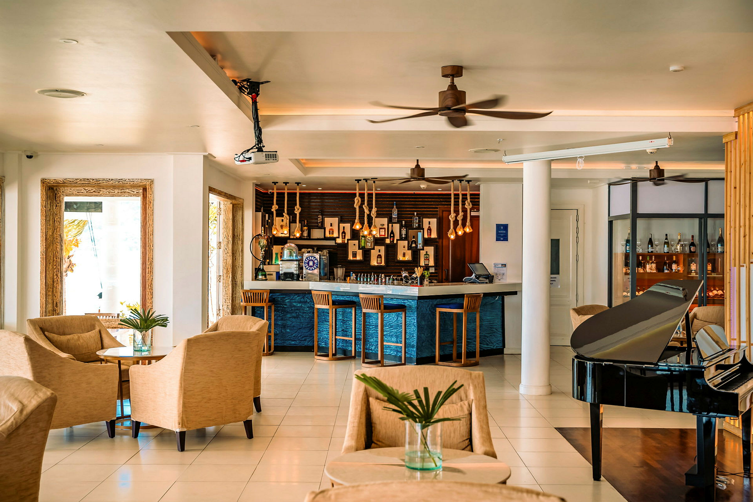 Hotellobby med sitteplasser, bar og svart piano. (AI-generert tekst)