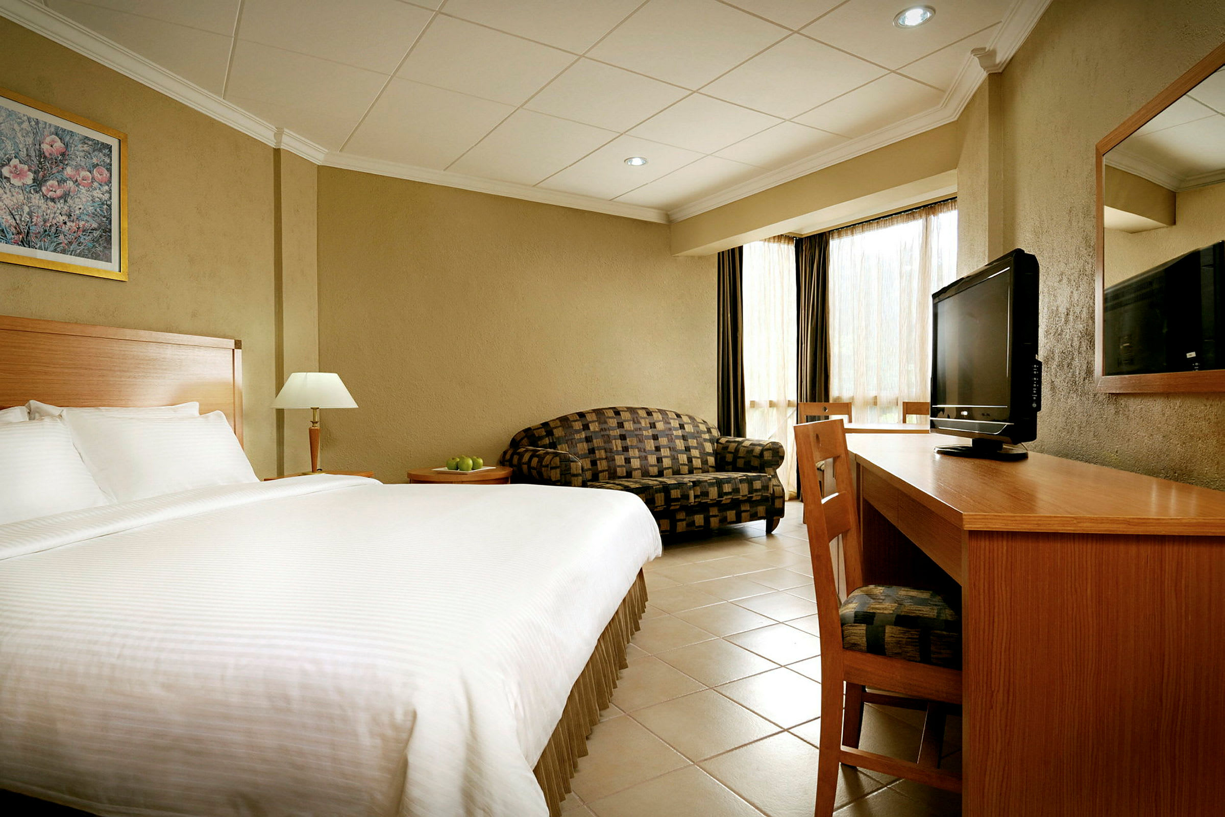Hotellrom med stor seng, skrivebord, TV og sofa. (AI-generert tekst)