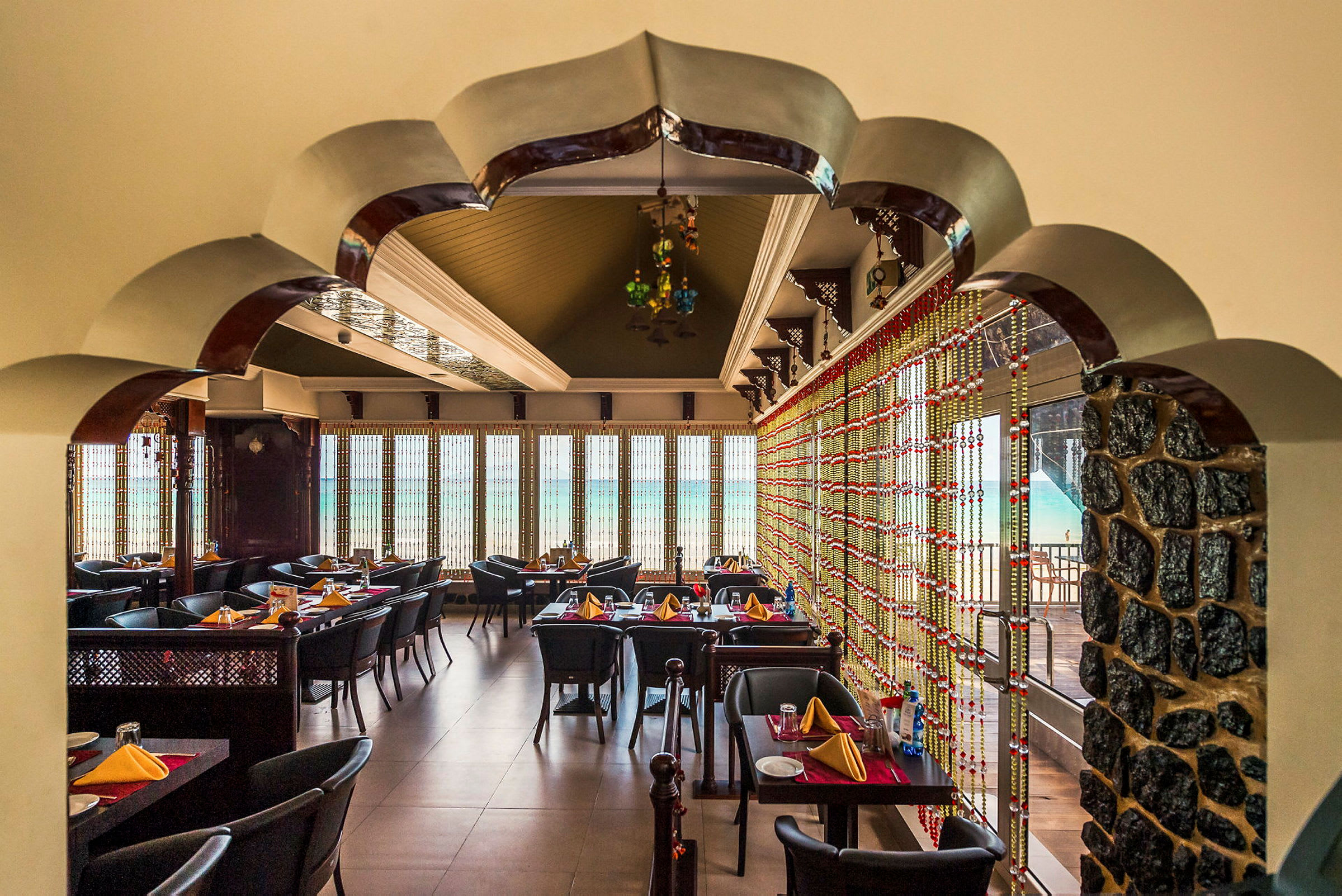 Et smakfullt innredet restaurantområde med bordoppstillinger og dekorative detaljer, som en vindusvegg med utsikt. (AI-generert tekst)