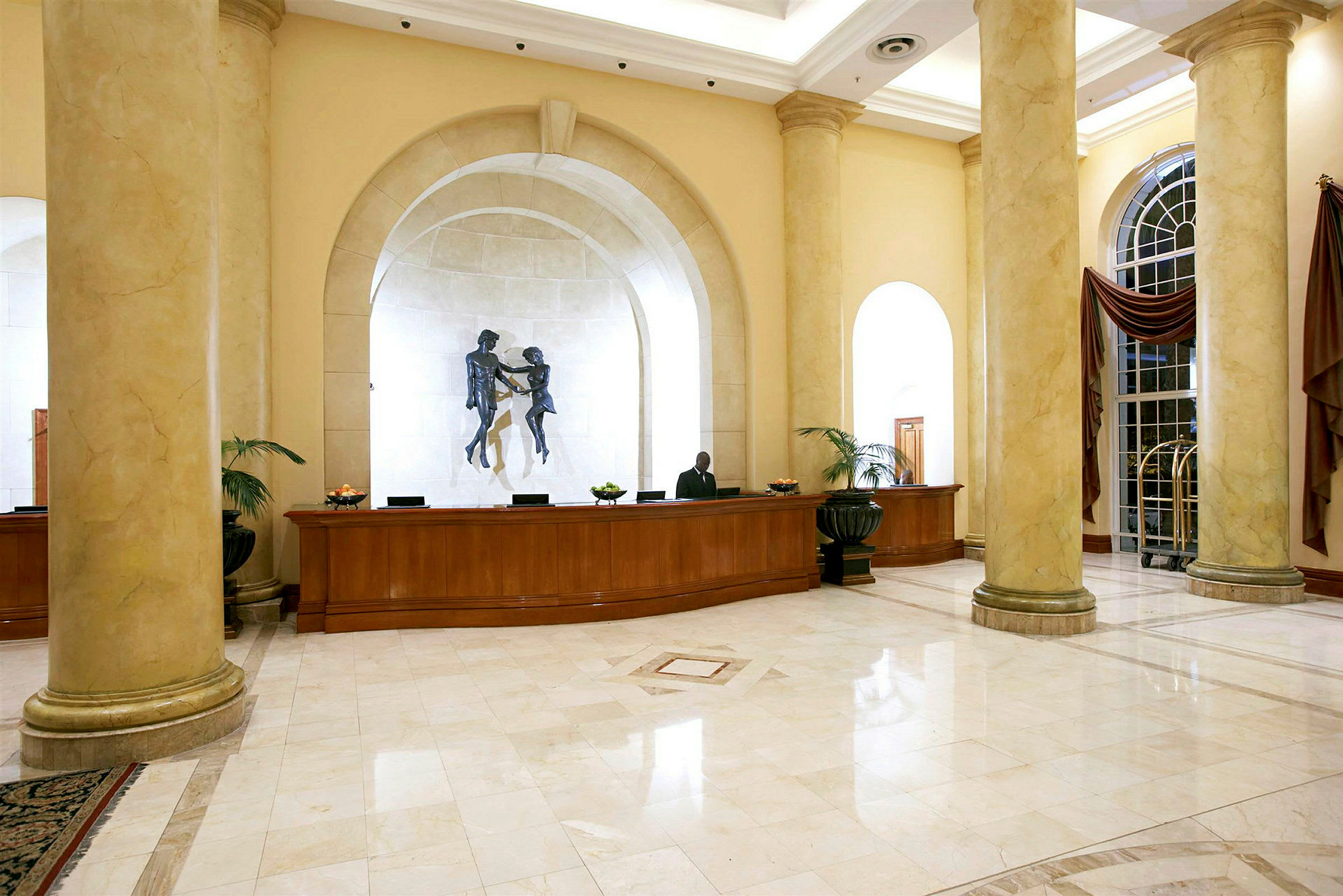 Hotellobby med resepsjonsdisk, søyler og veggpynt. (AI-generert tekst)