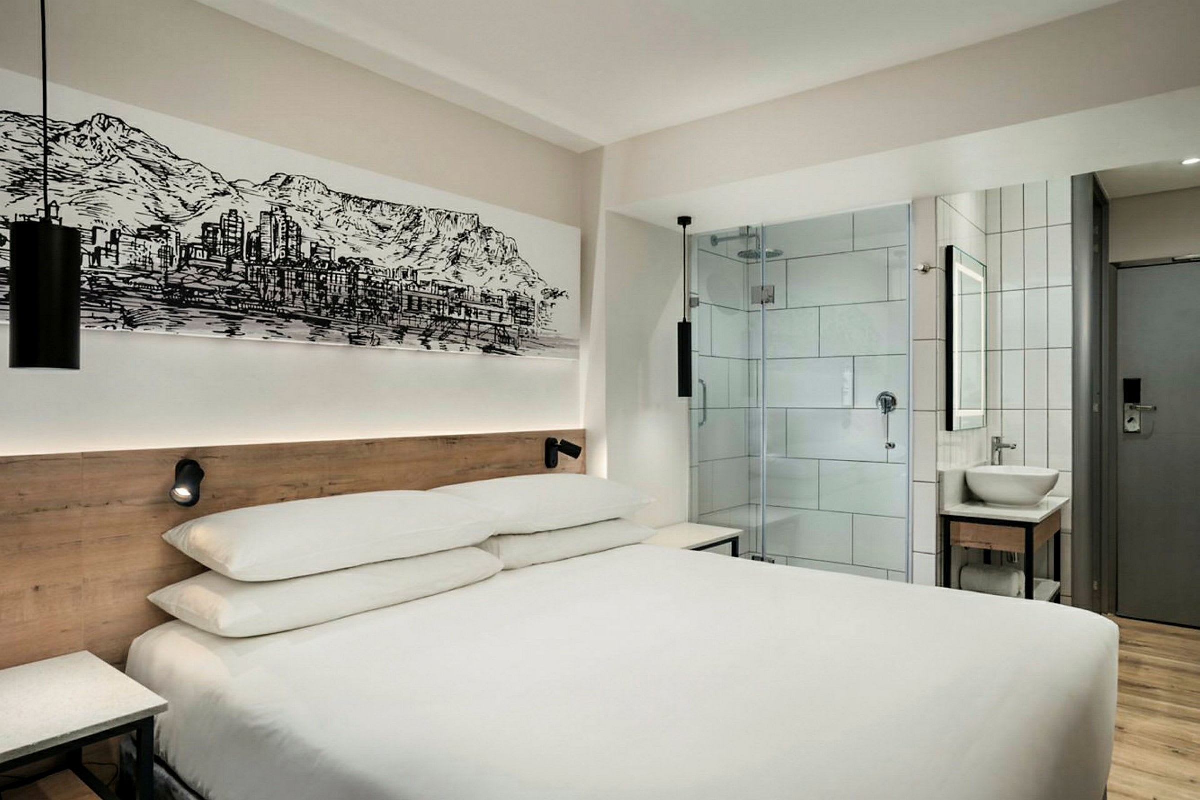 Moderne hotellrom med en dobbeltseng, glassdør til badet og veggkunst. (AI-generert tekst)