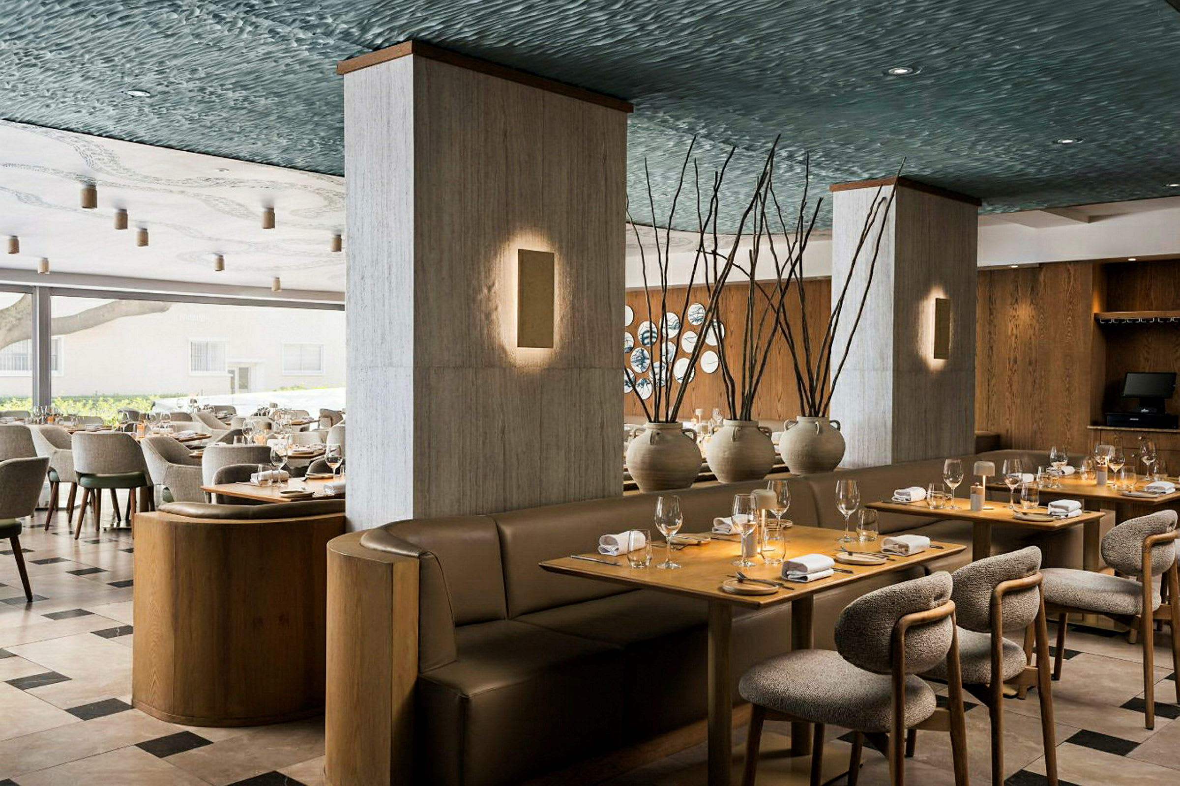 En elegant restaurantinteriør med dekkede bord, polstrede stoler og komfortable sofaer. Dekorasjoner inkluderer keramikkvaser og tregulv. (AI-generert tekst)