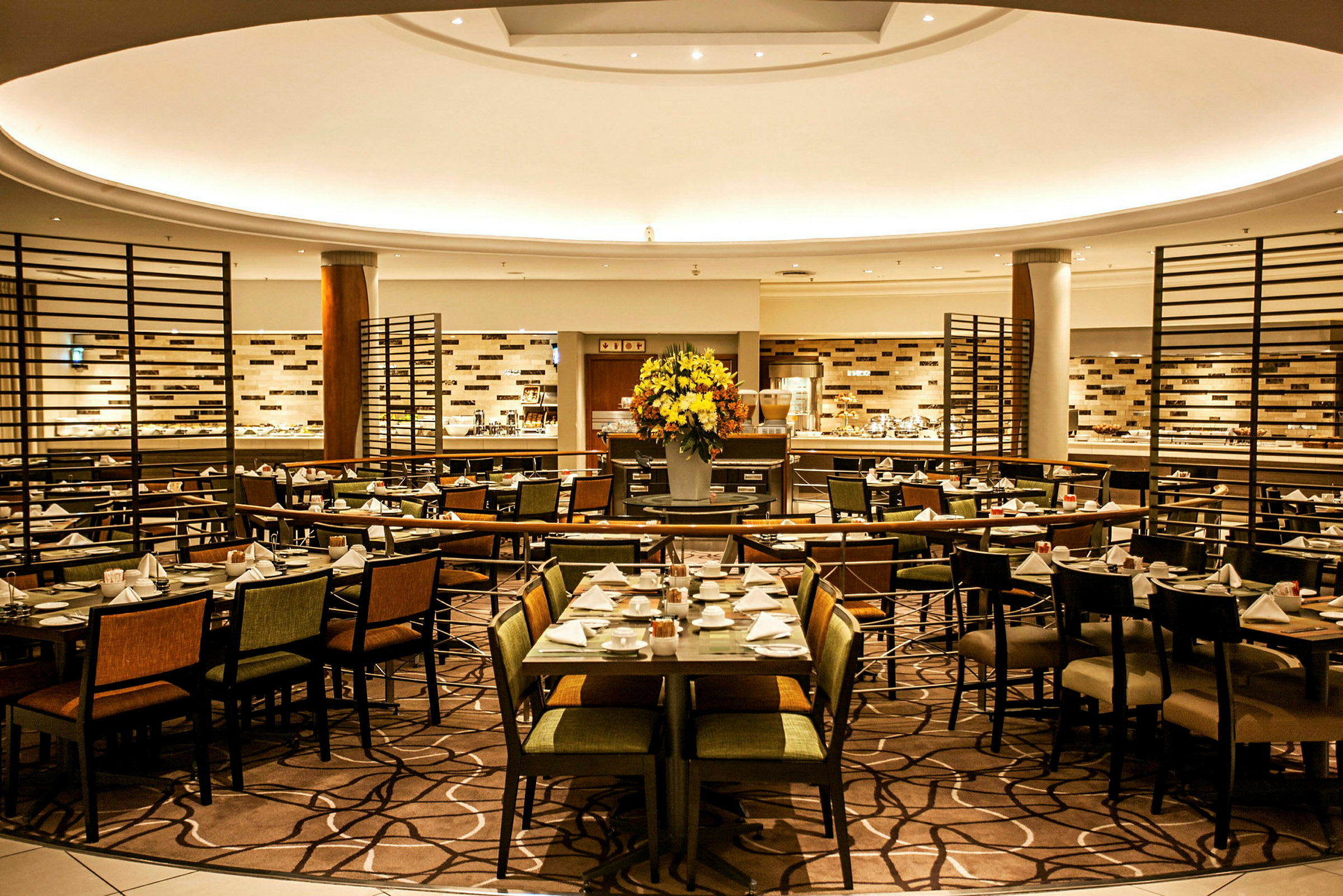 Et interiørbilde av en elegant restaurant med dekket bord og en stor blomsterbukett i midten. (AI-generert tekst)