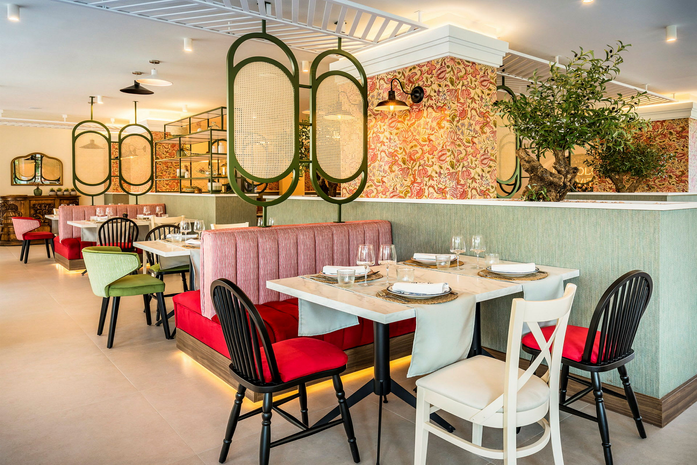 Interiør av en restaurant med bord, stoler og båsplasser. Dekorasjoner inkluderer planter og fargerike tapeter. (AI-generert tekst)