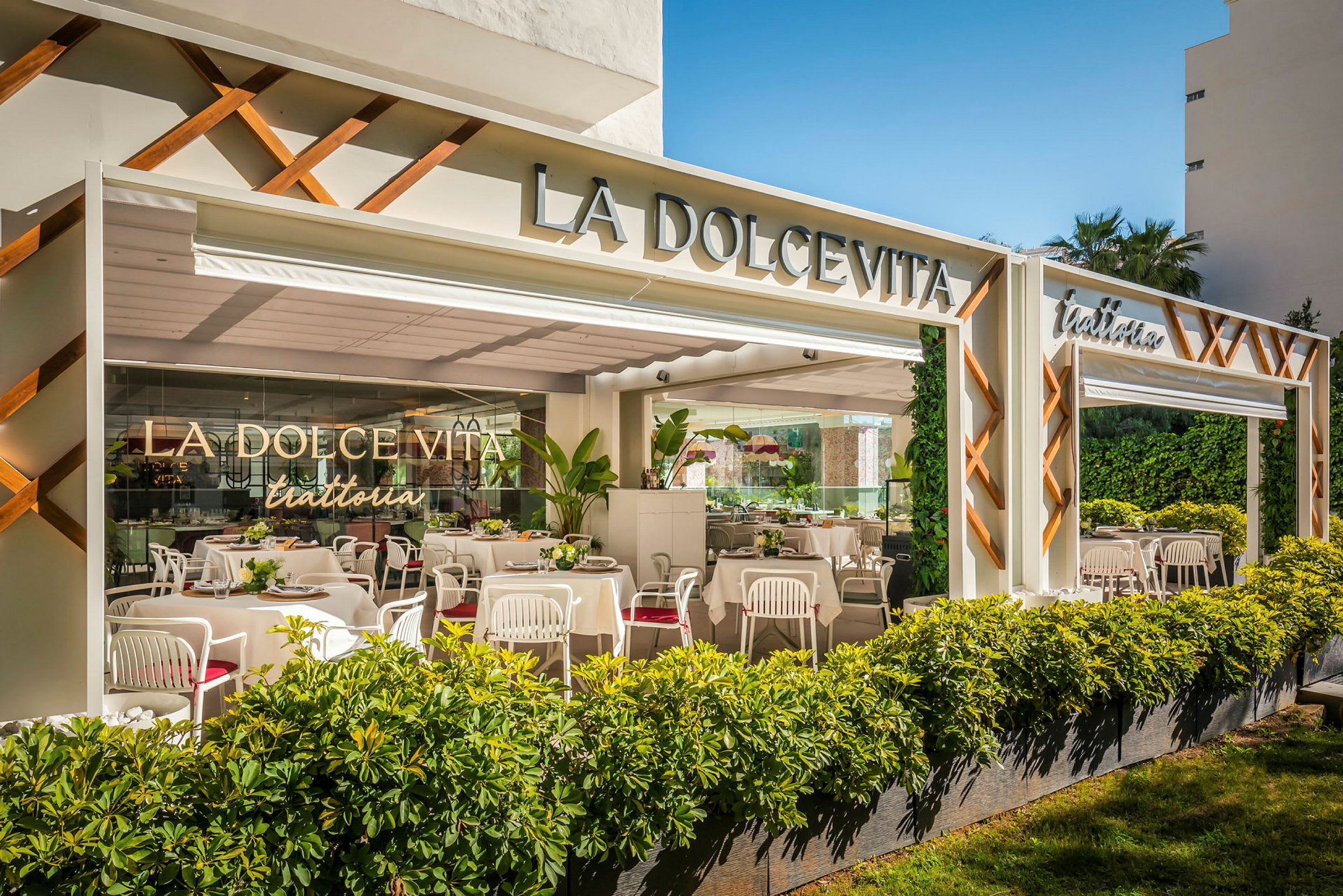 Bilde av fasaden til en restaurant med navnet La Dolce Vita og en åpen uteplass med bord og stoler. (AI-generert tekst)